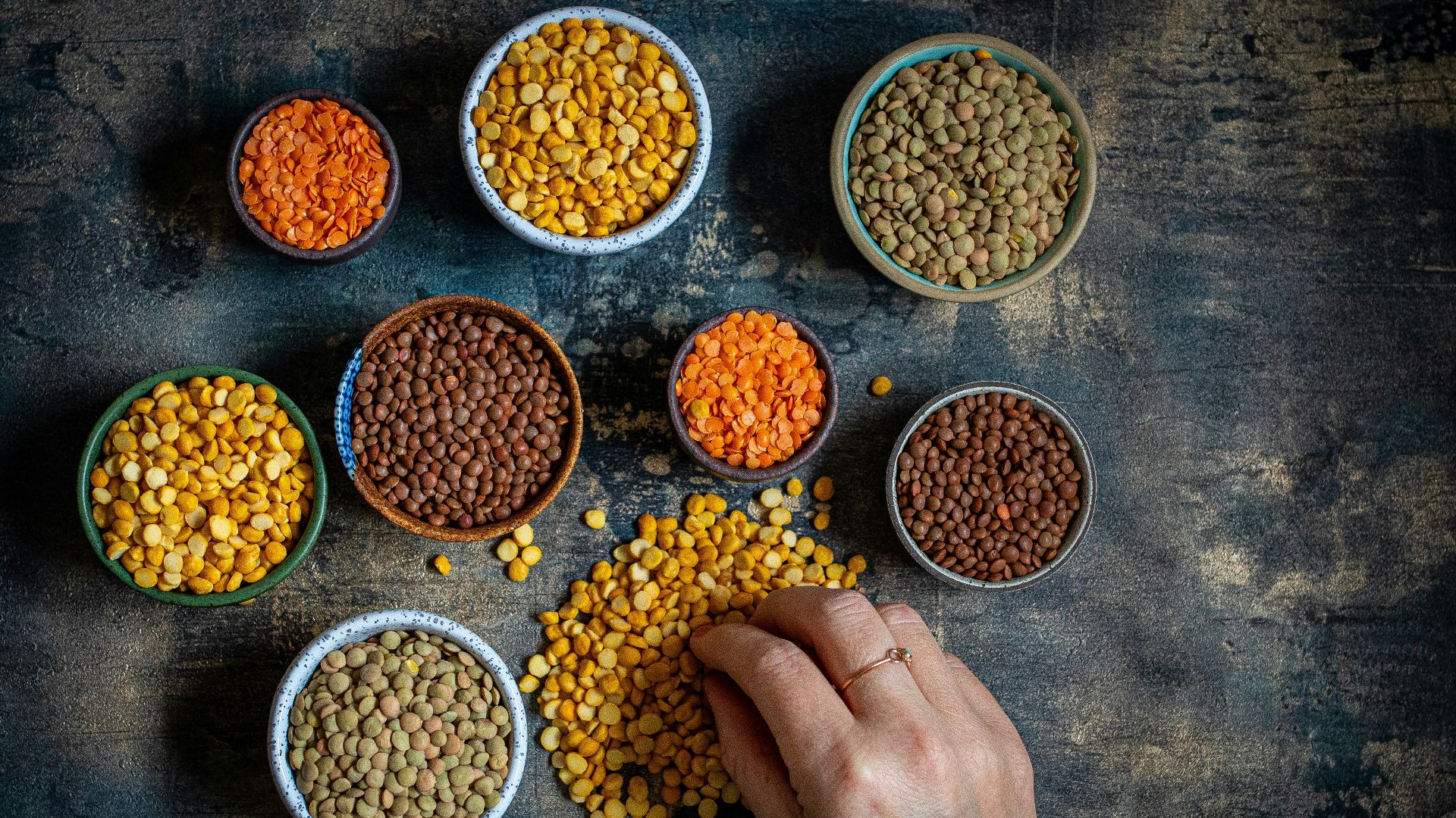 a person touching a bowl of lentils on a table