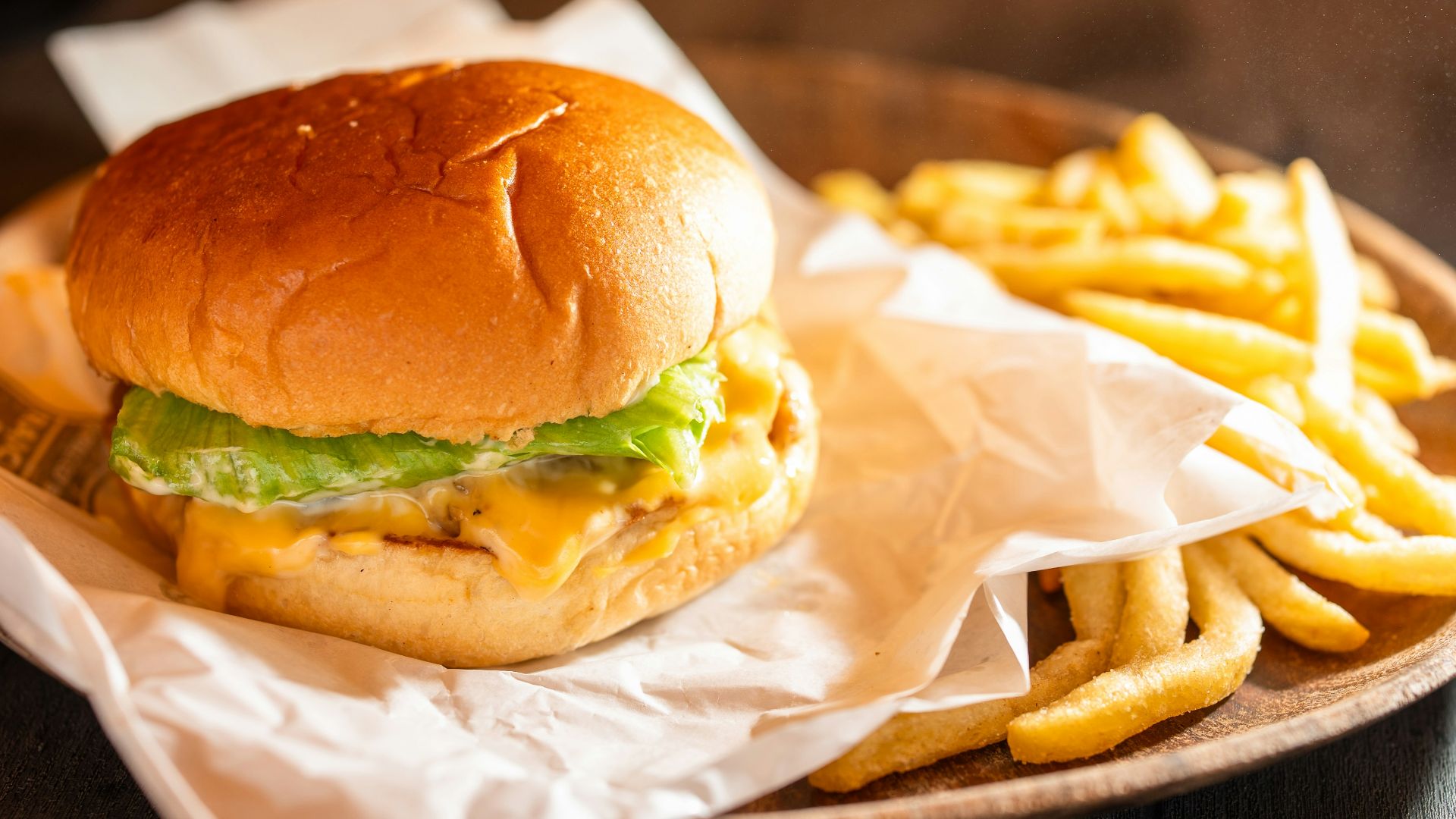 A juicy burger with fries on a wooden plate
