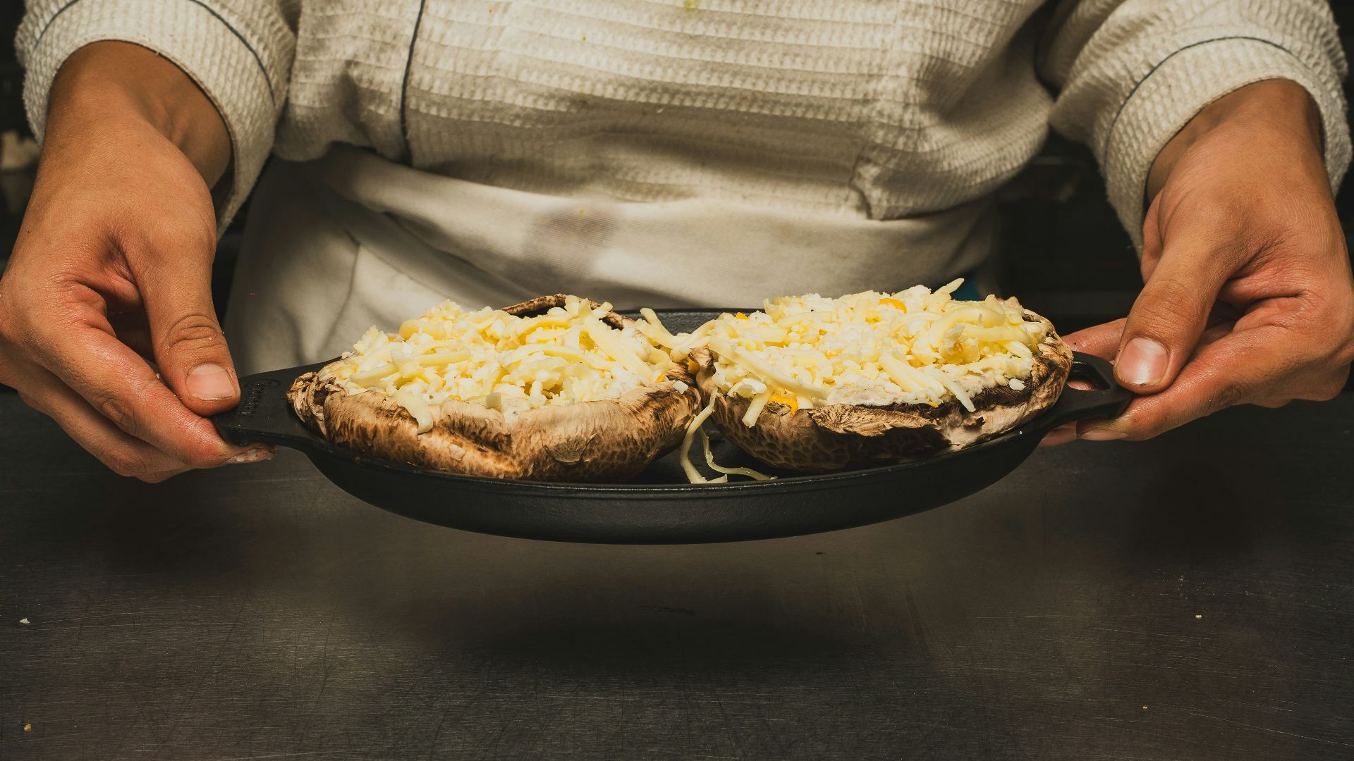 A chef holds two mushroom dishes.