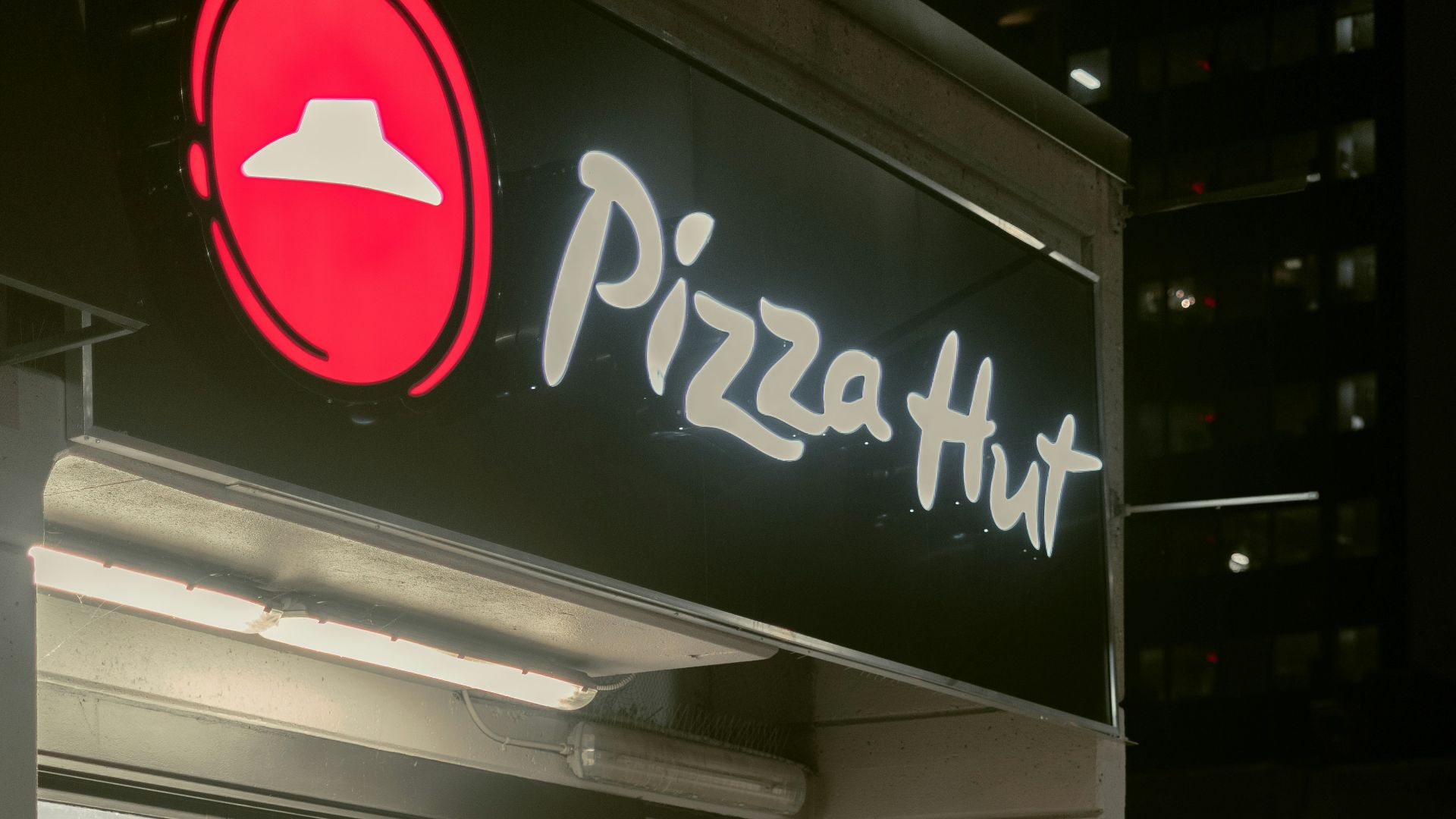 a man riding a bike past a pizza hut