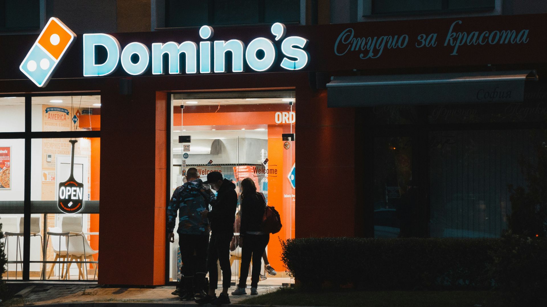 a group of people standing outside of a domino's store