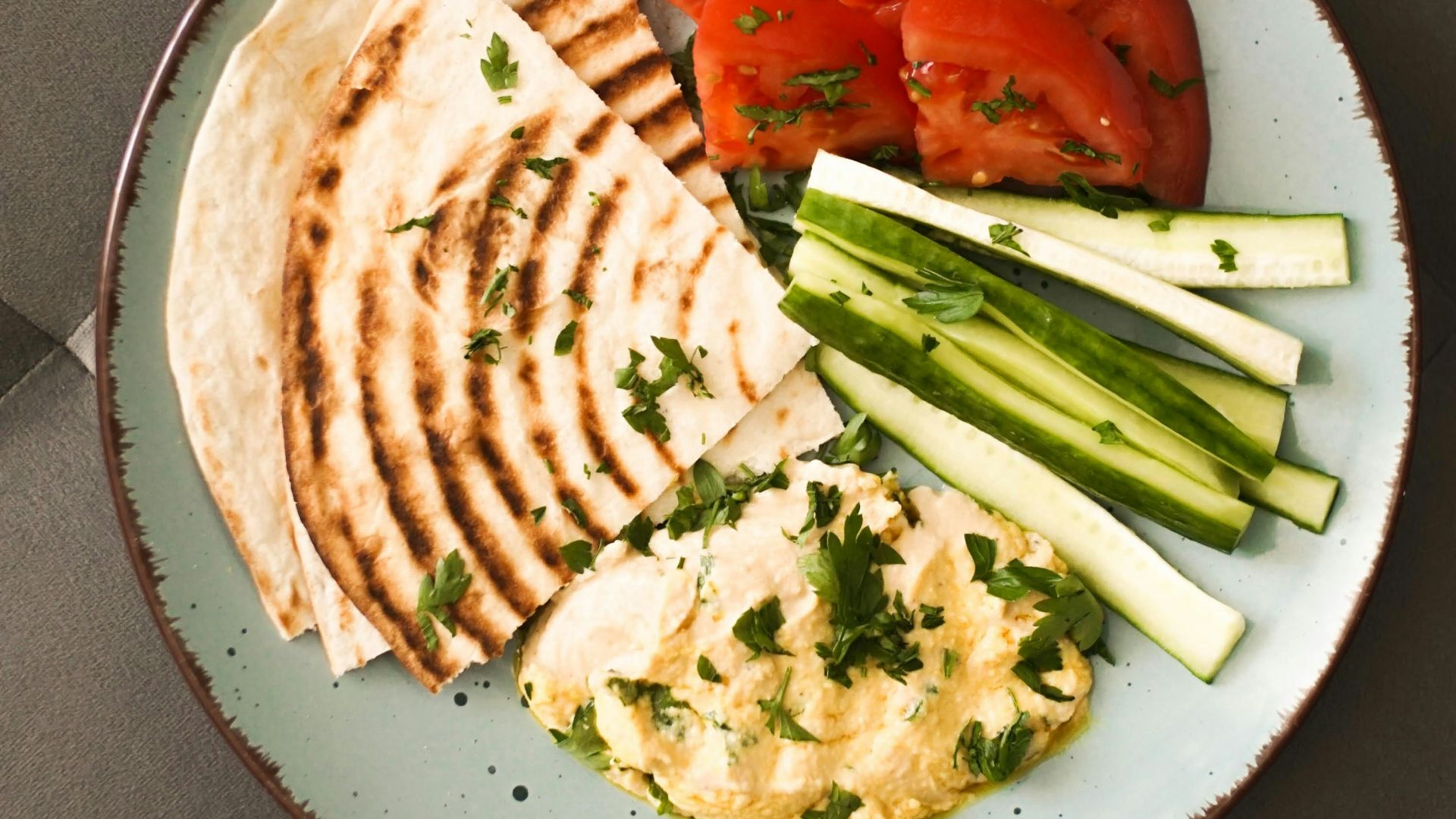 a plate of food that includes pita bread, tomatoes and cucumbers