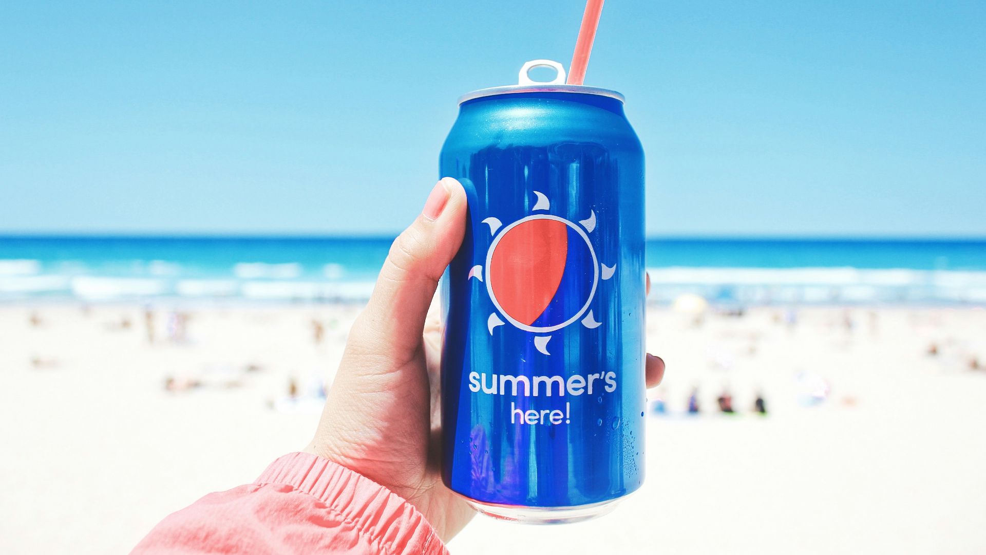 person holding Pepsi soda can on seashore