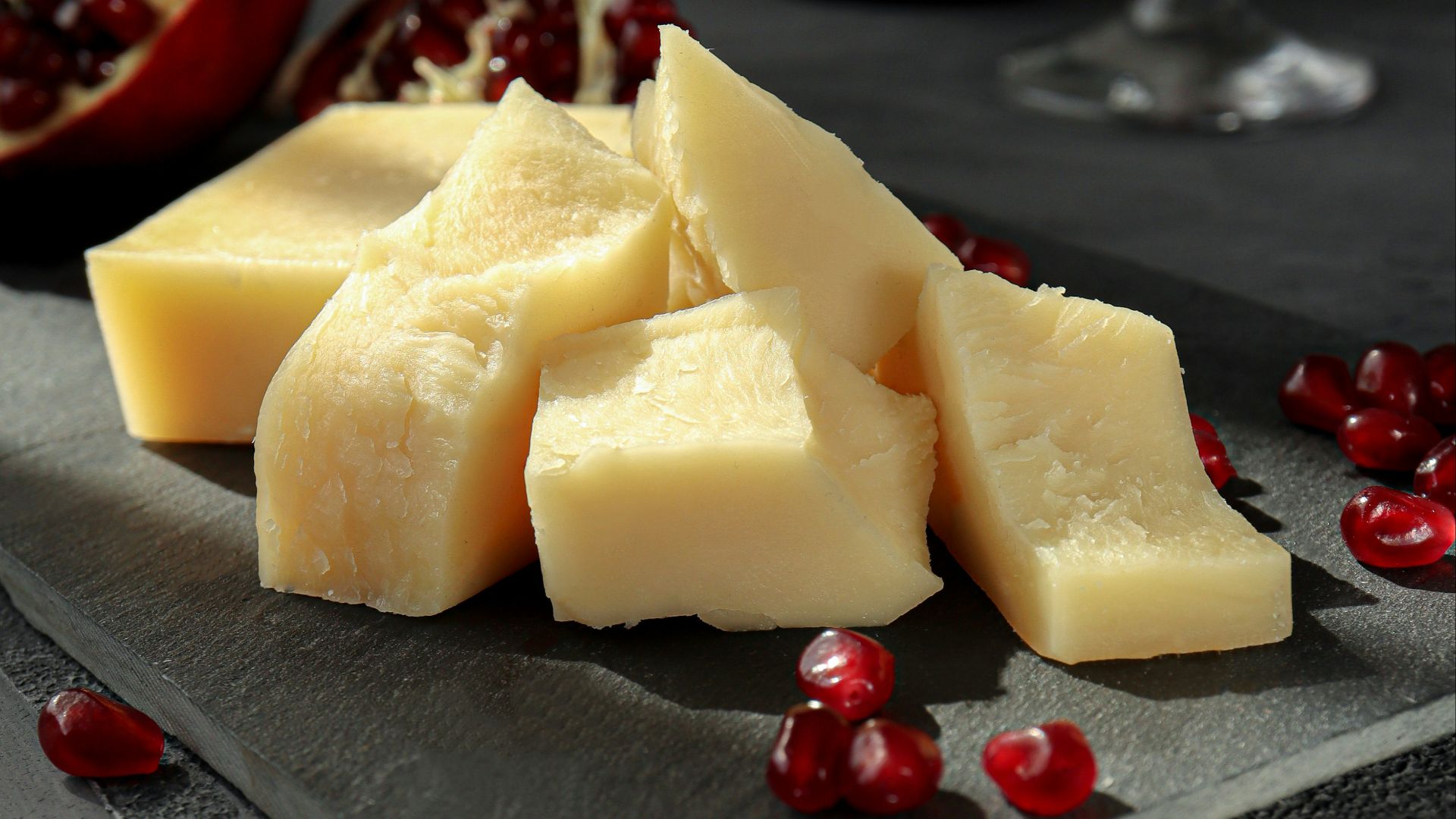 sliced cheese on black plate beside wine glass