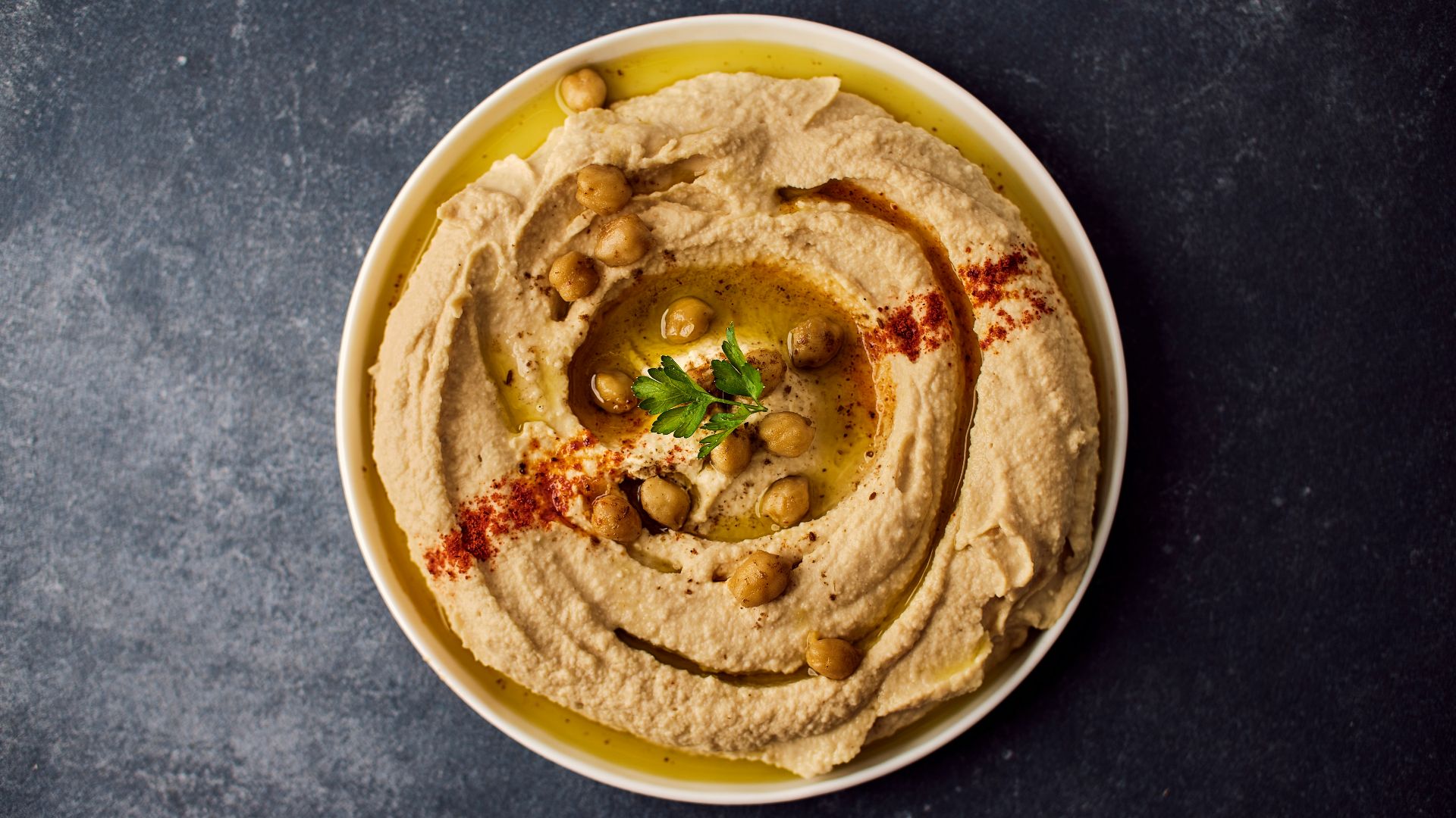 a bowl of hummus with a garnish on top