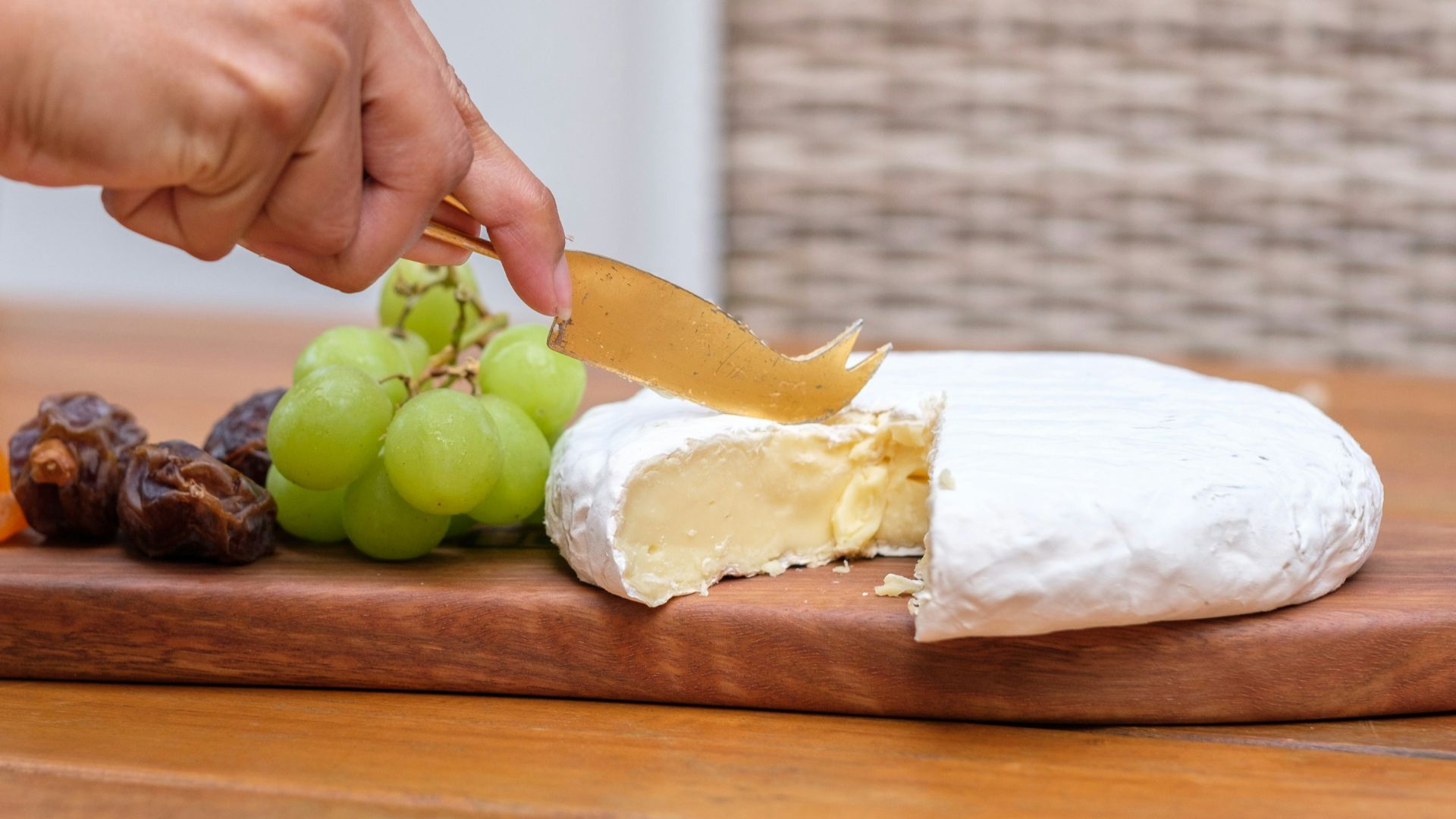 A person cutting a piece of cheese on a cutting board