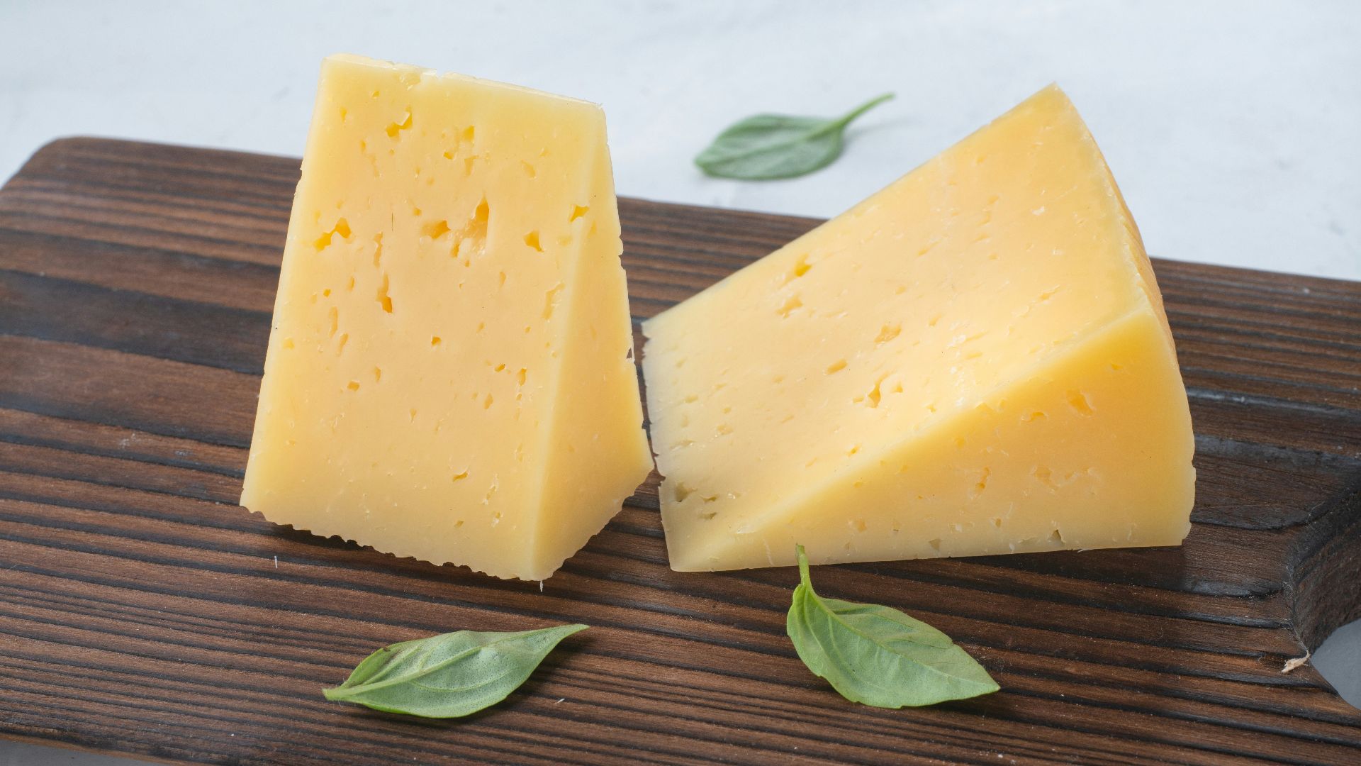 a couple of pieces of cheese sitting on top of a wooden cutting board