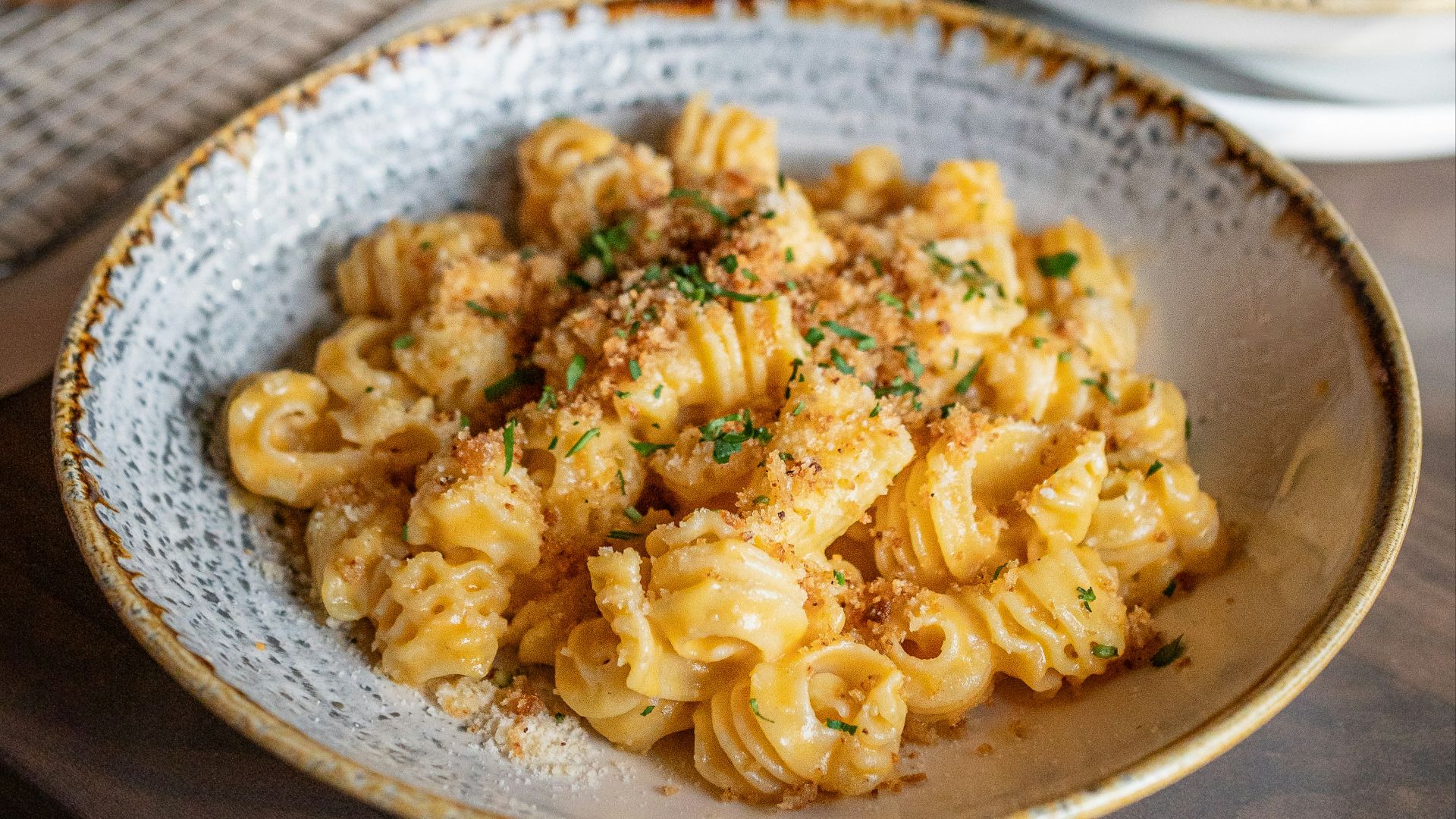a bowl of pasta and a plate of pizza on a table