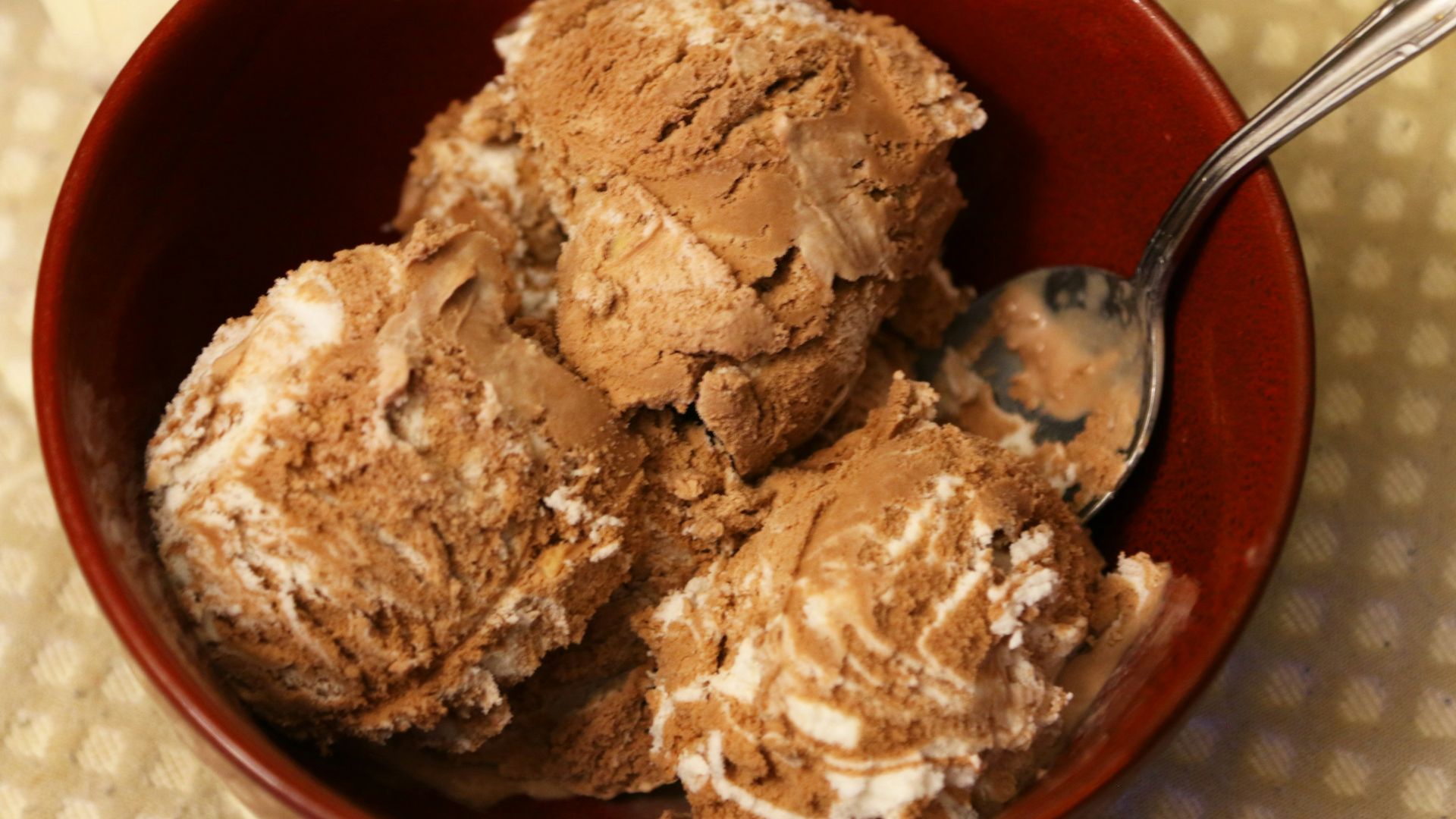 Chocolate ice cream with white swirls in a red bowl.