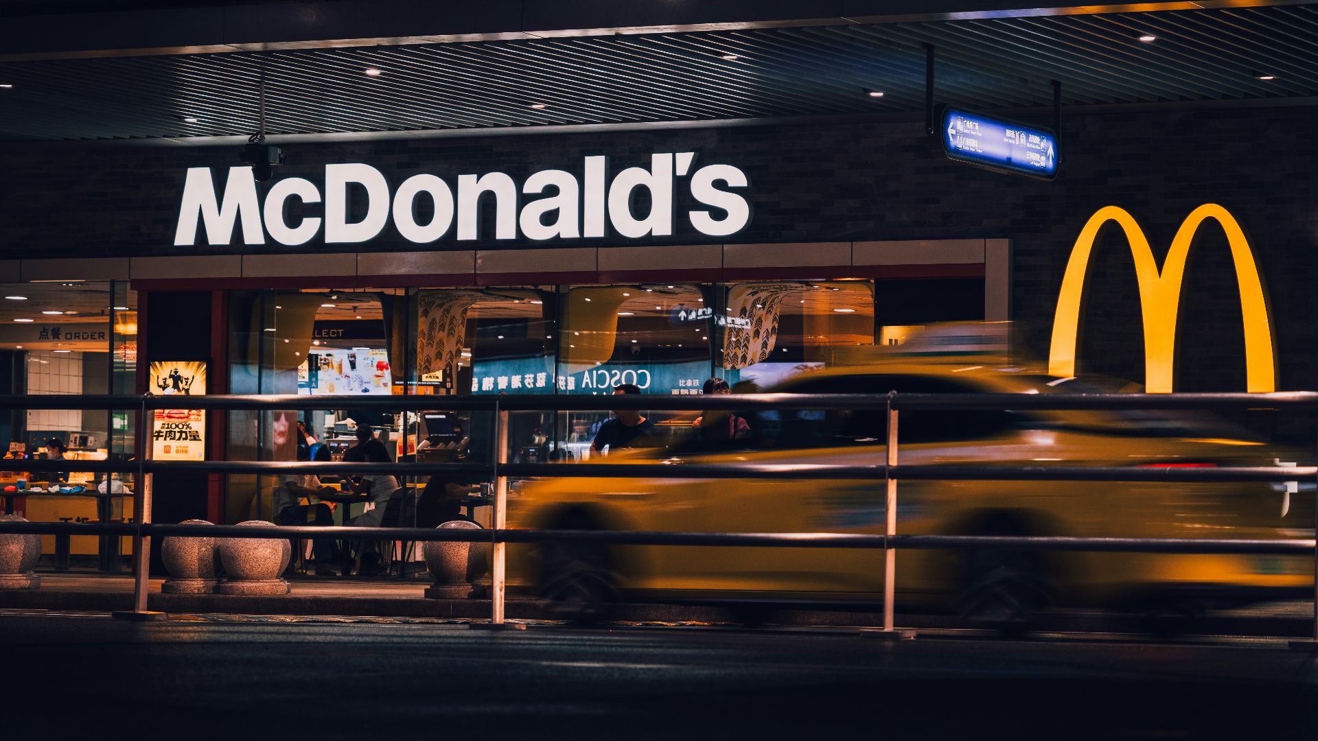 Mcdonald's at night with a passing car.