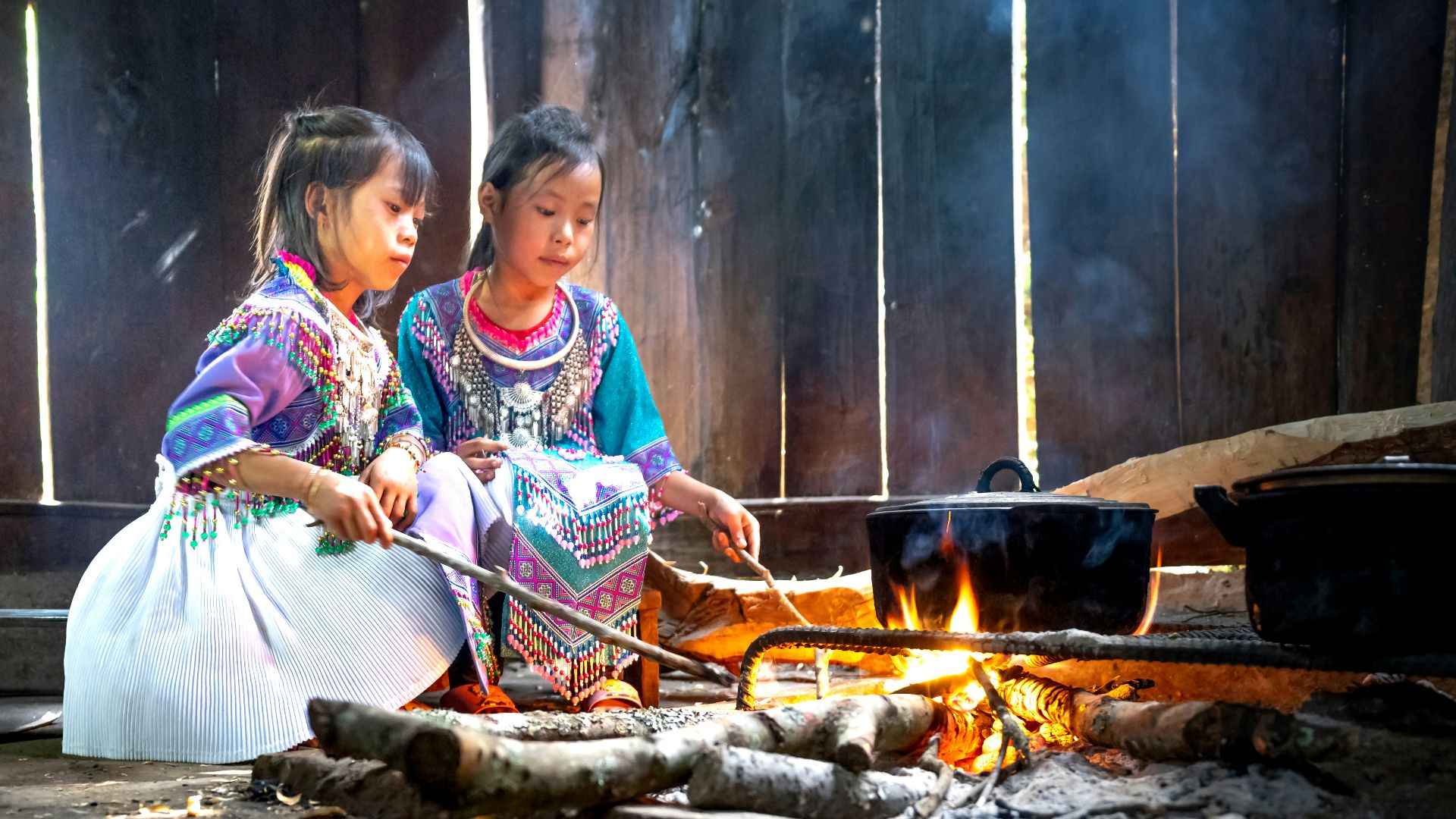two young girls cooking food over a fire