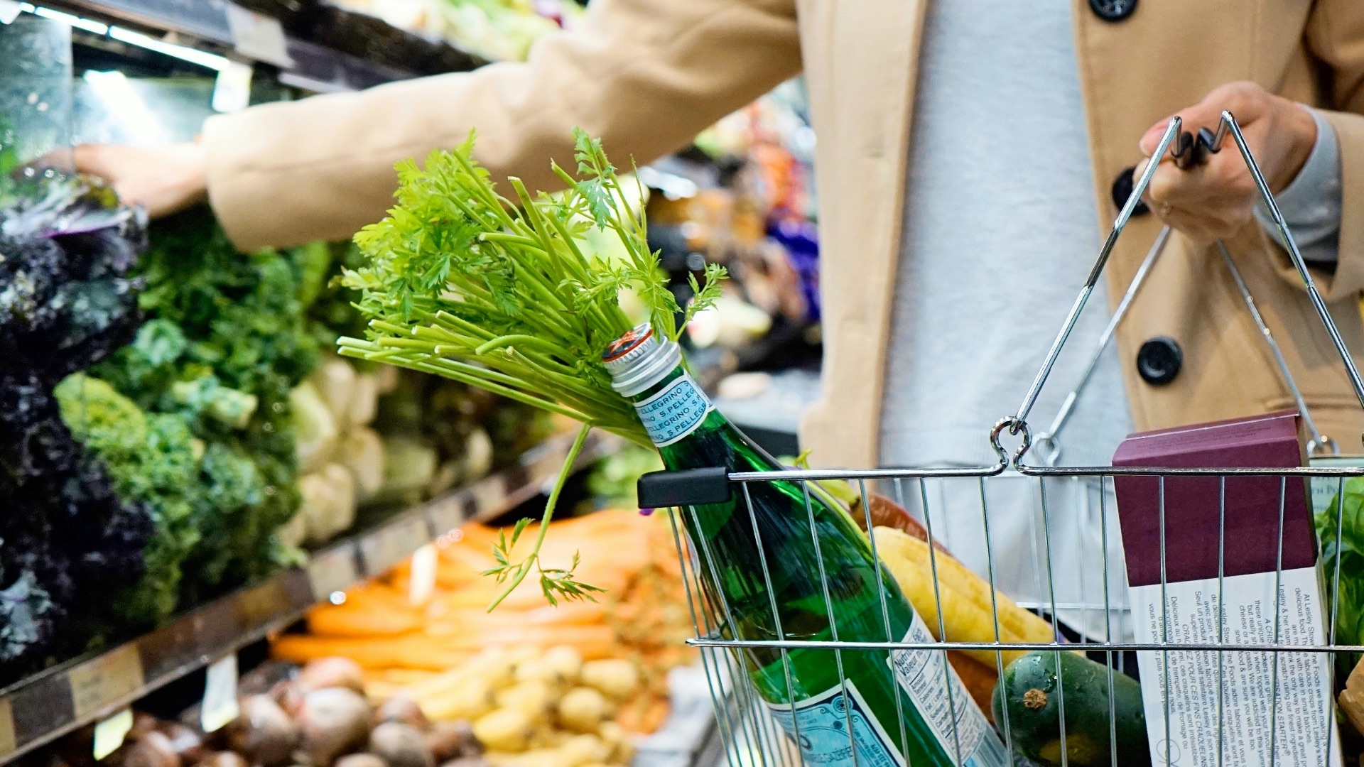 woman in white coat holding green shopping cart