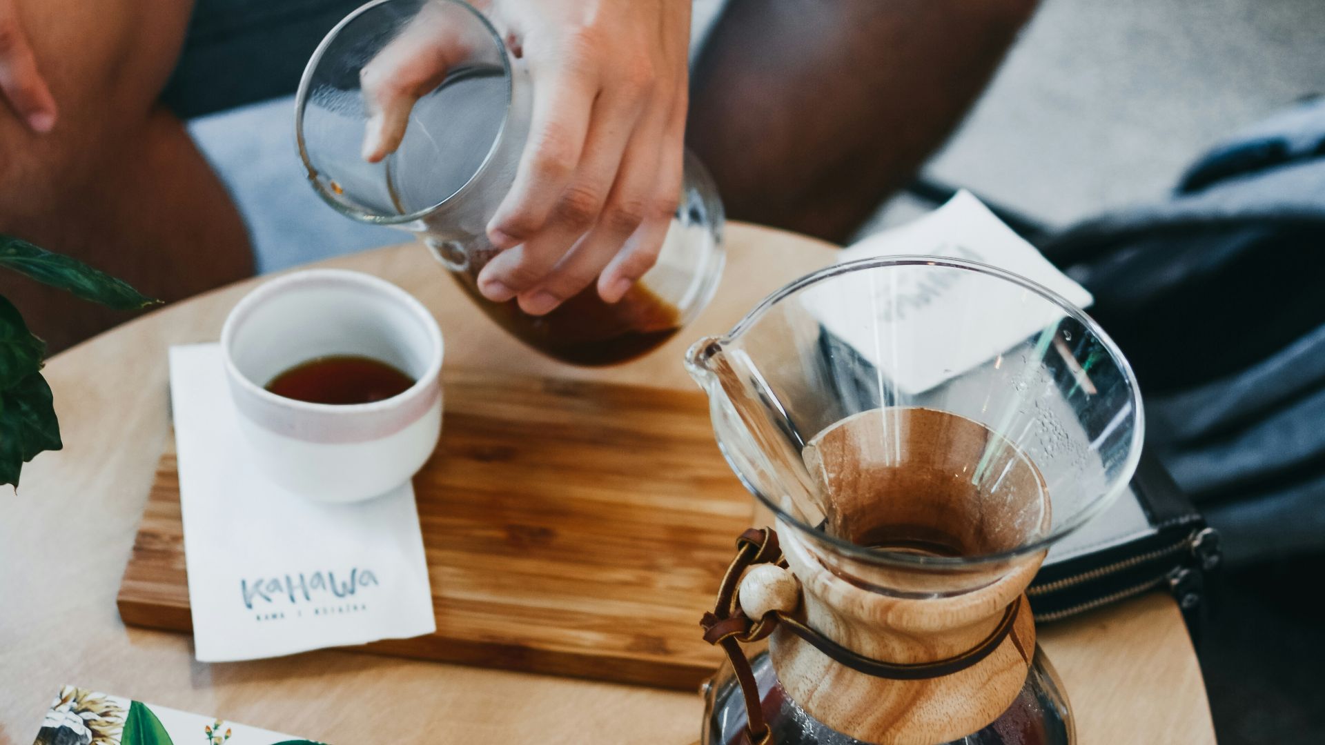 person about to pour tea on teaup while on coffee table