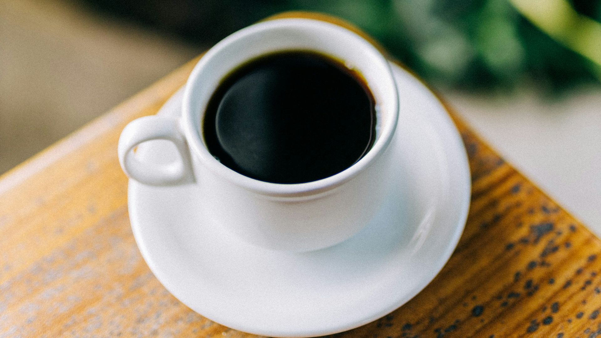 a cup of coffee sitting on top of a wooden table