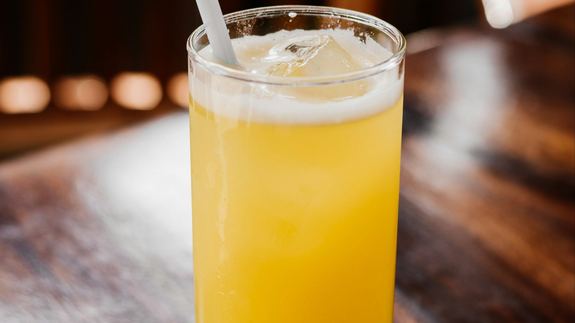 a glass of orange juice on a wooden table