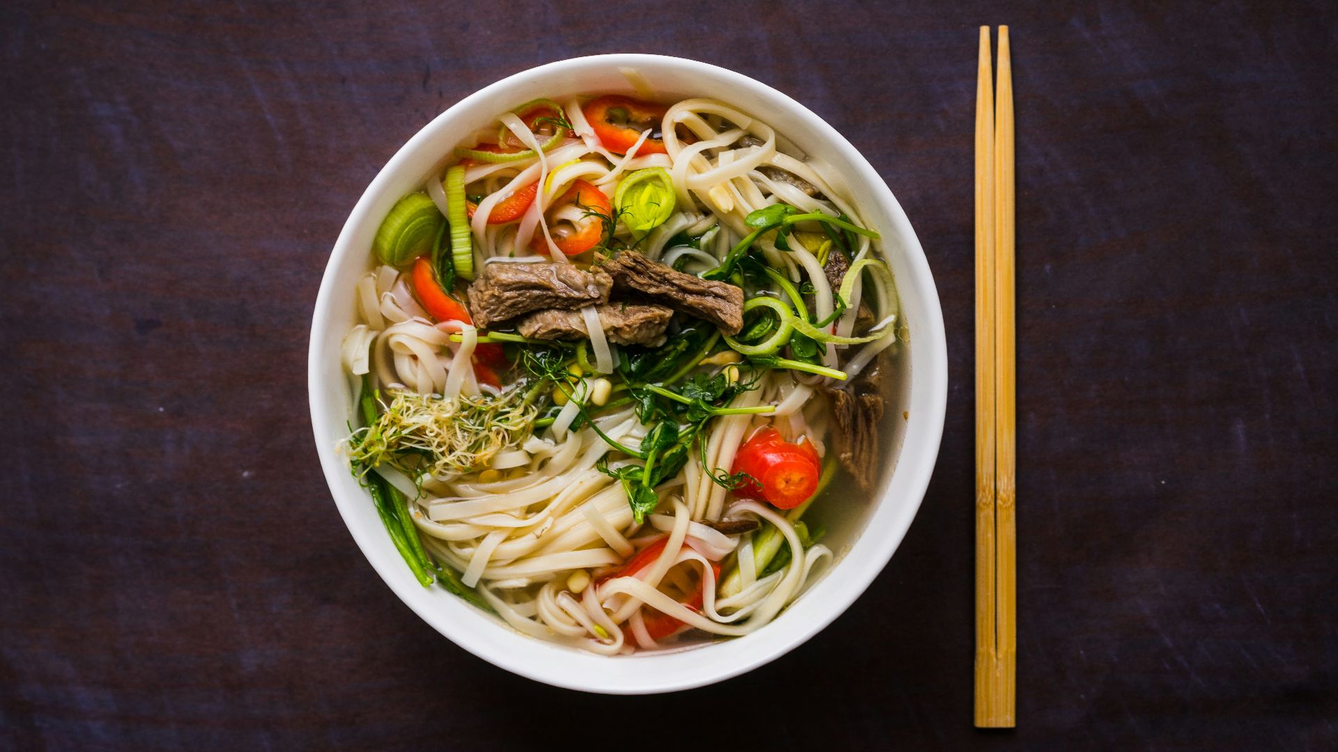 a bowl of noodle soup with chopsticks on the side