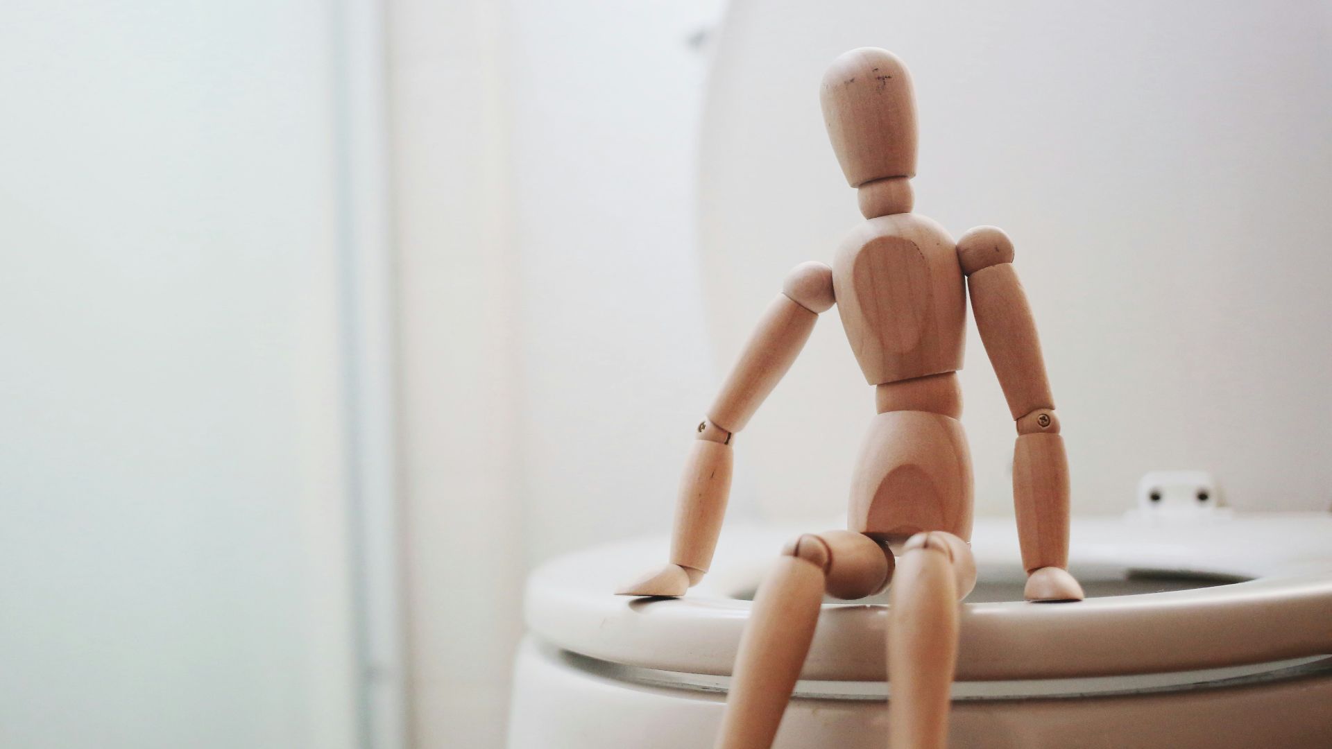 brown wooden doll on white ceramic toilet bowl