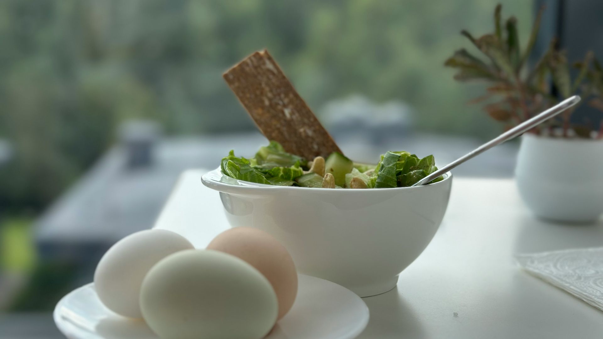A bowl of salad and two eggs on a table