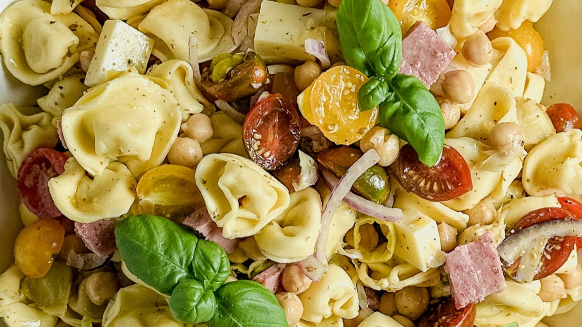 Tortellini salad with tomatoes, ham, and basil.