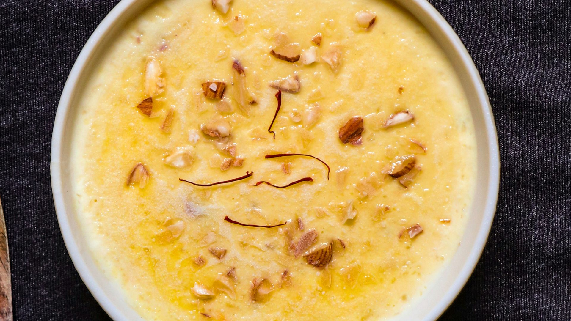 white ceramic bowl with soup beside brown wooden spoon