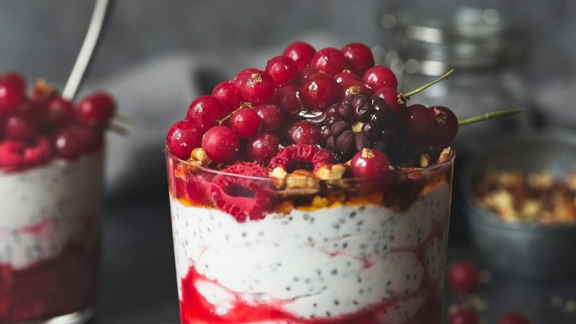 A spoon is lifting a spoonful of berries out of a jar