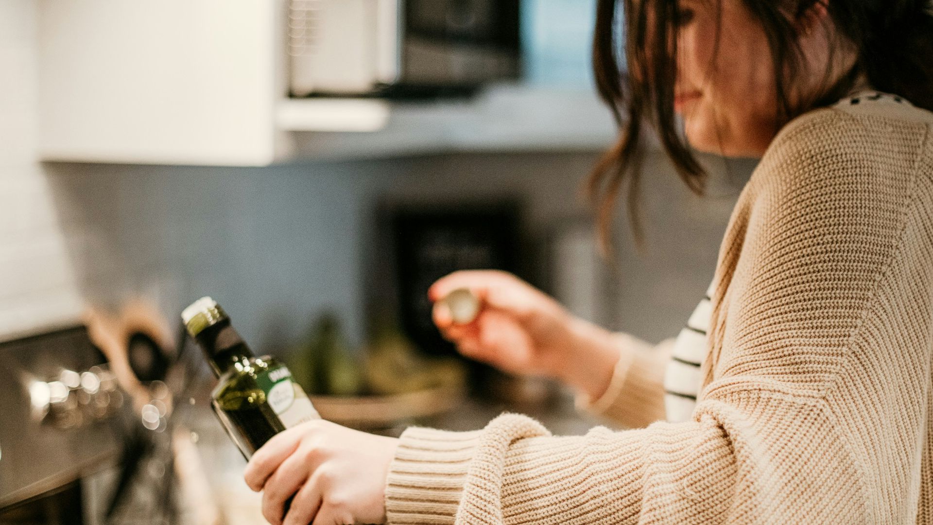 woman in white long sleeve shirt holding bottle