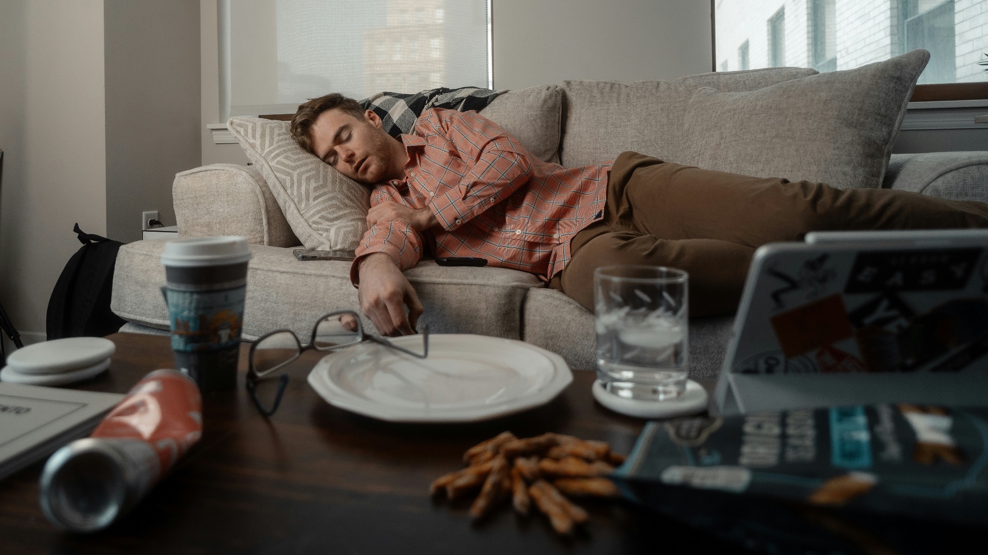 a woman laying on a couch with a plate of food