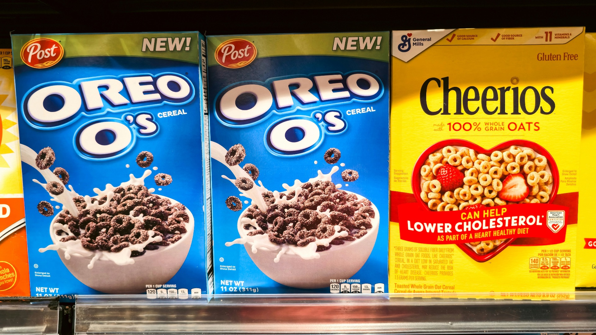 Boxes of oreo o's and cheerios cereal on shelf.
