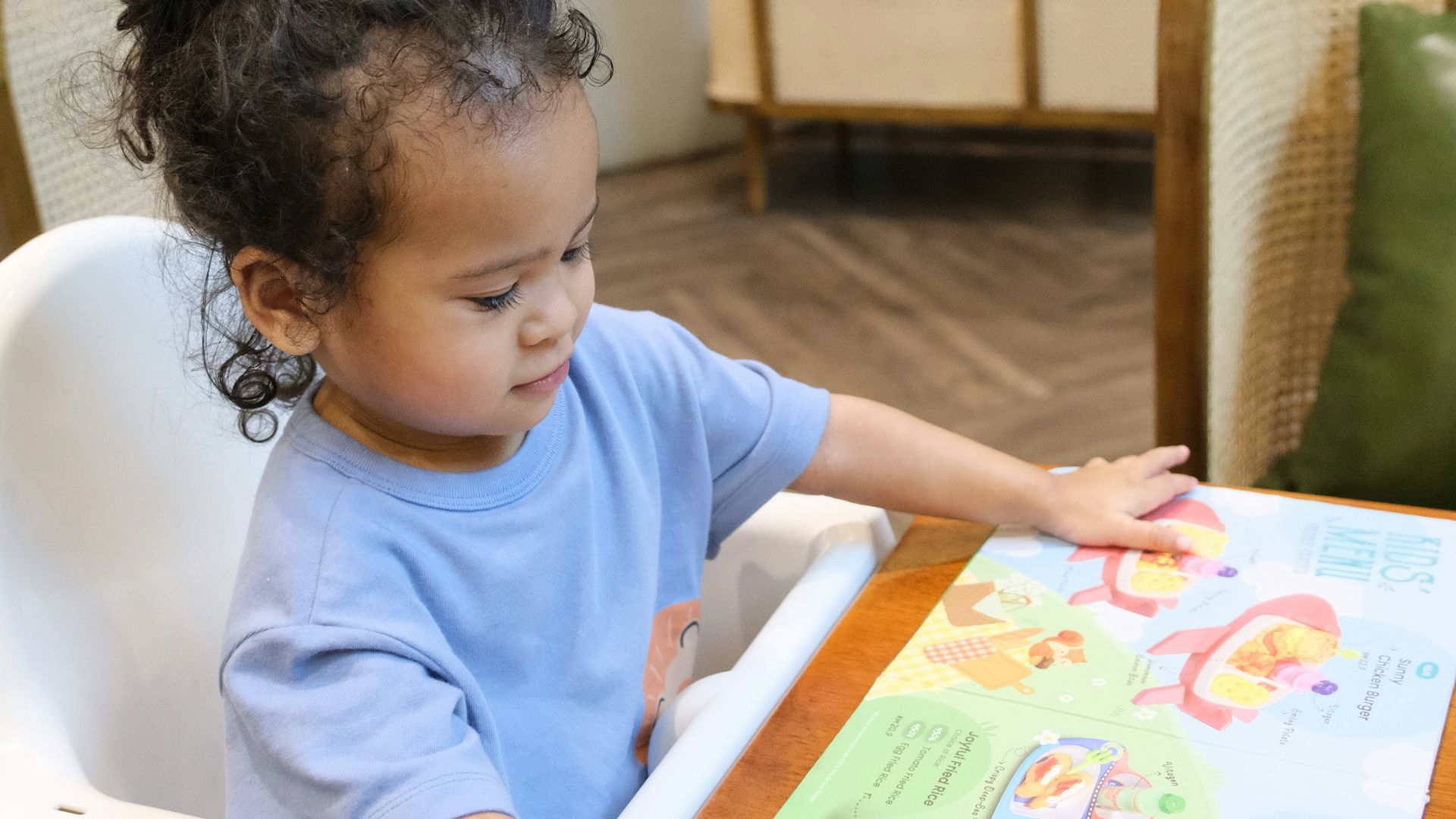 Young child pointing at a colorful menu.
