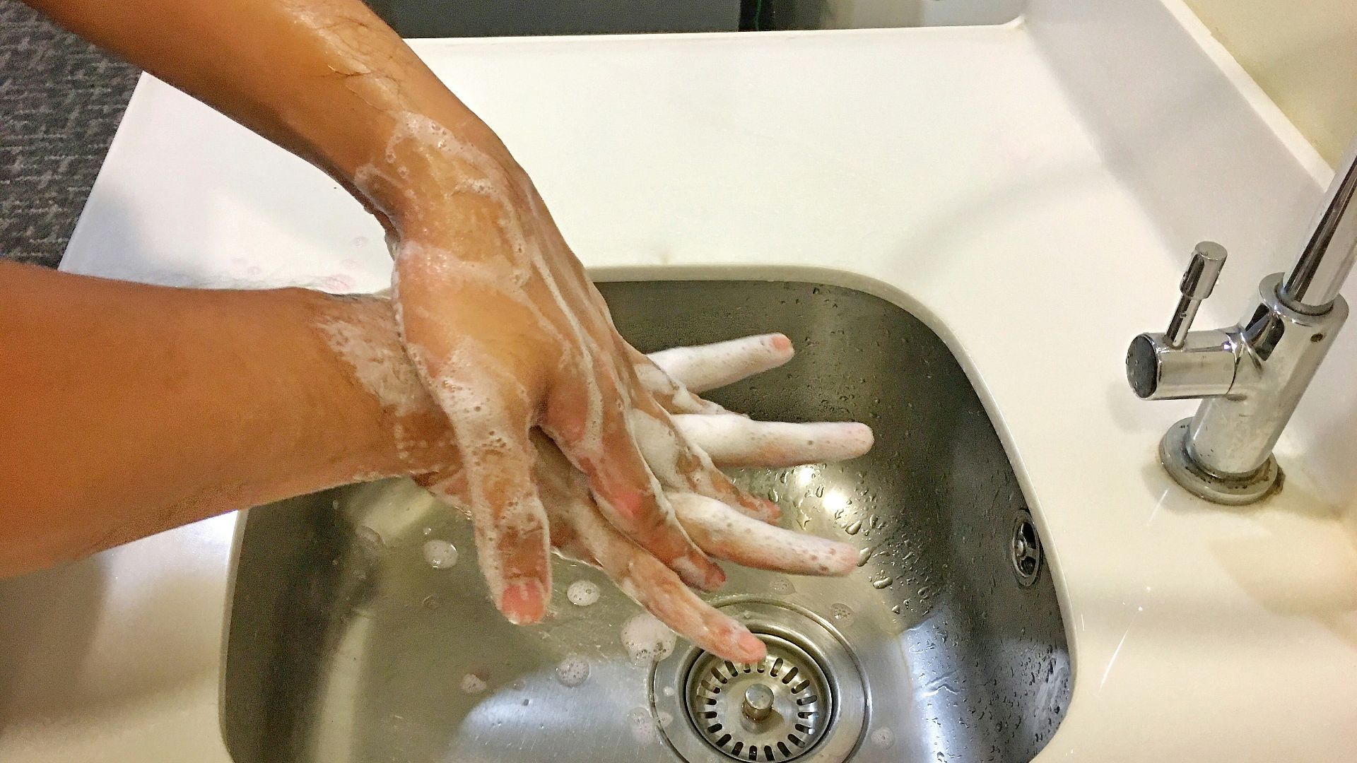person washing hands on sink