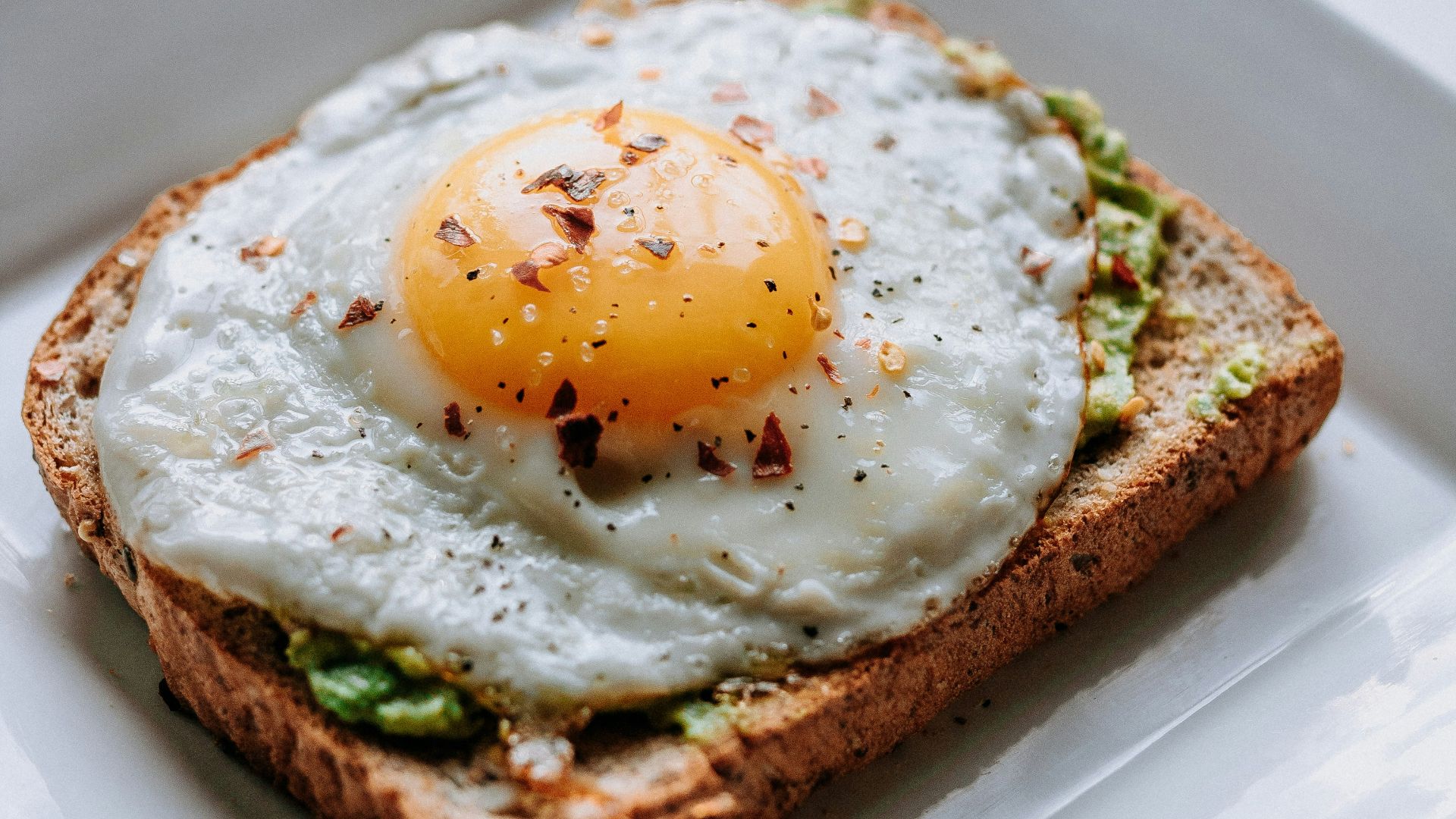 bread with sunny side-up egg served on white ceramic plate