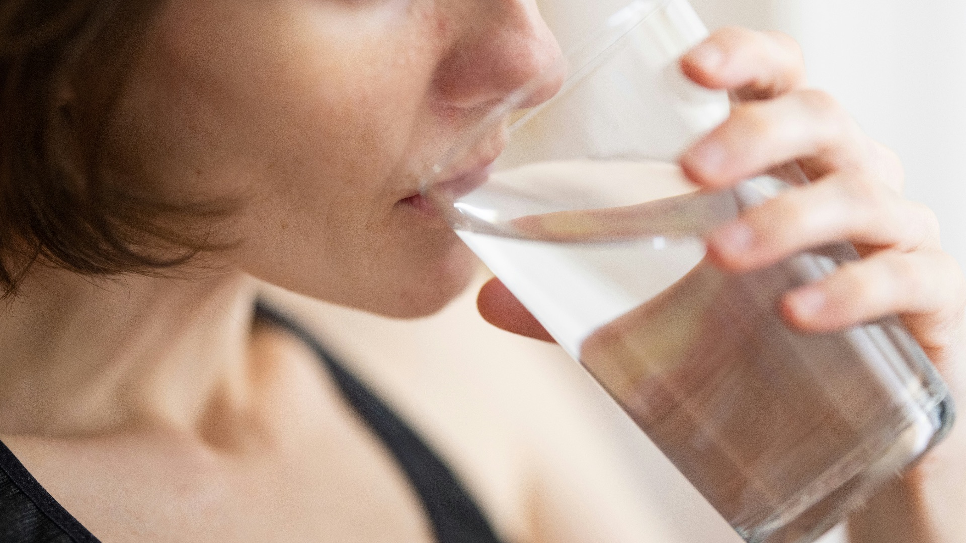 woman in black tank top drinking water
