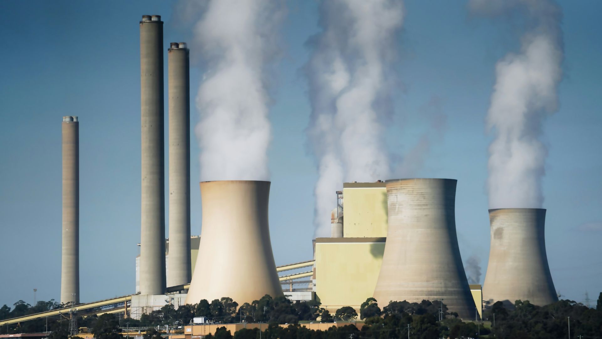 smoke billows from the cooling towers of a power plant