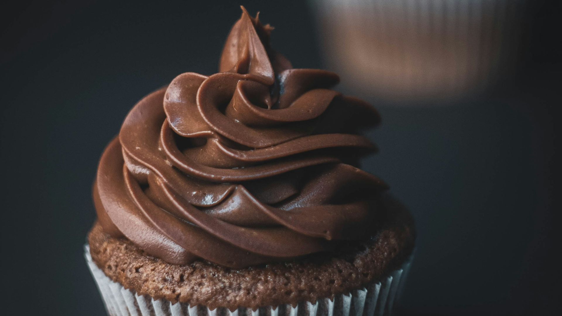 a chocolate cupcake with chocolate frosting on a black background