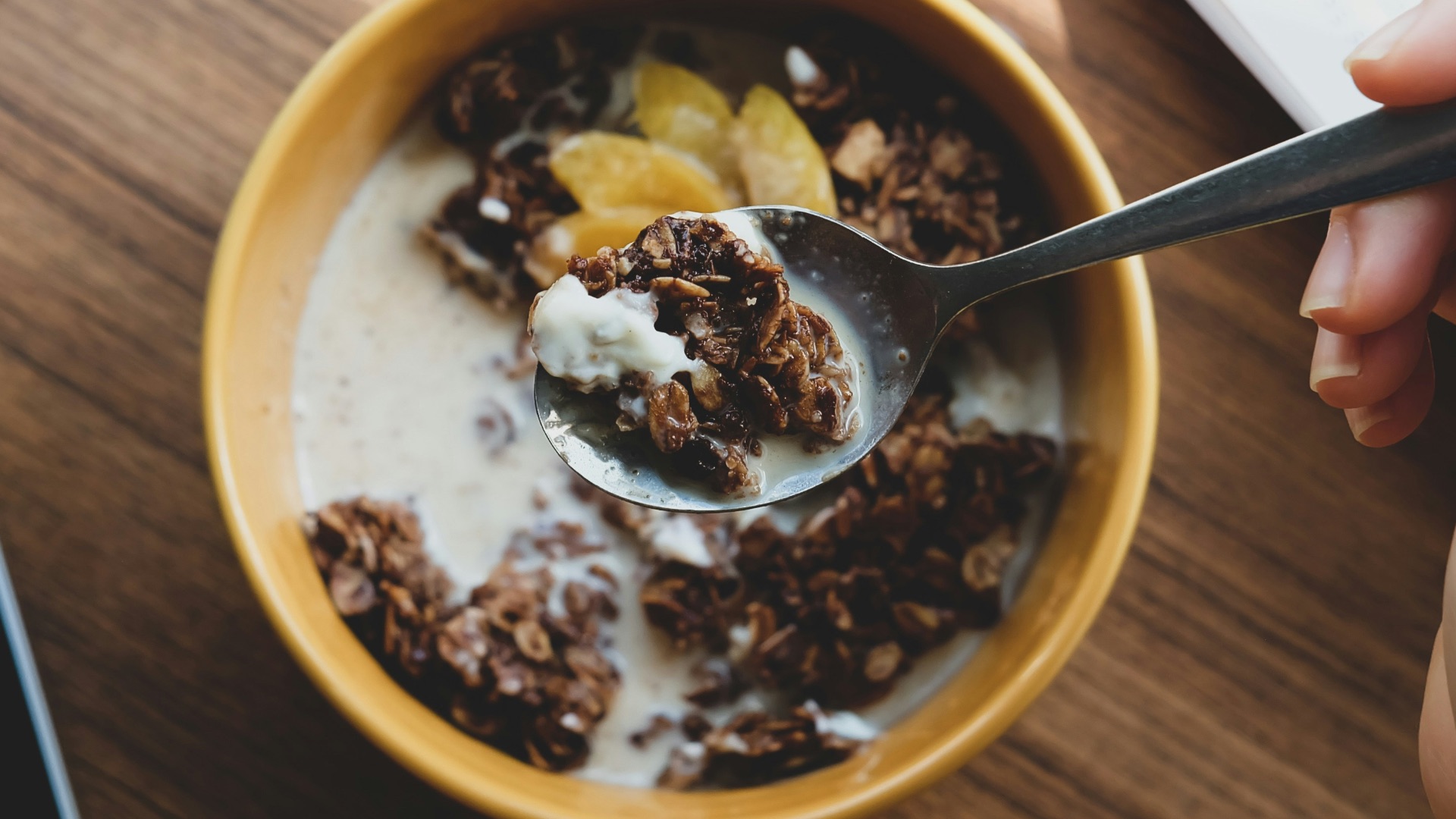 person holding silver spoon on brown ceramic bowl