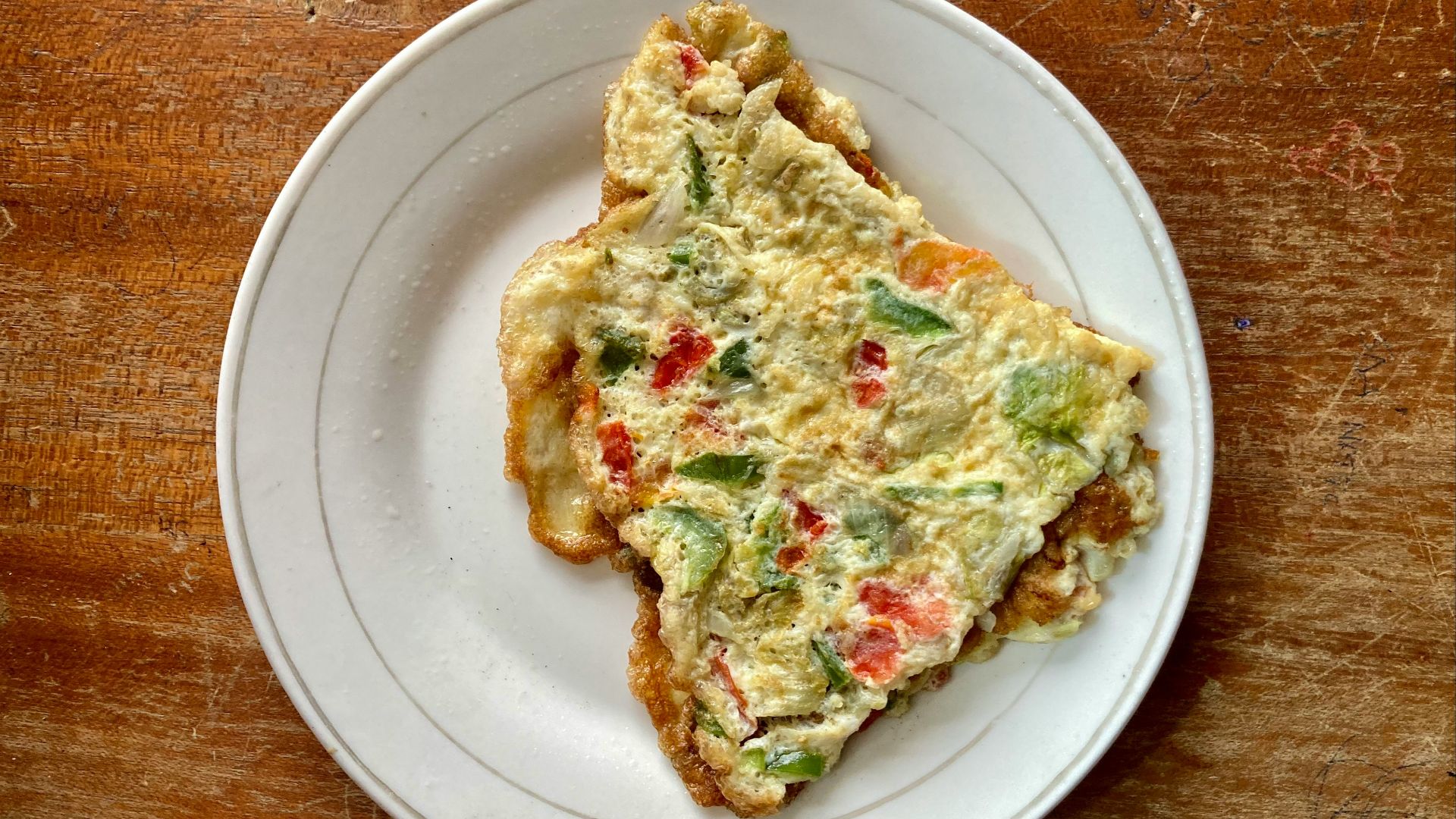 a slice of quiche on a white plate on a wooden table