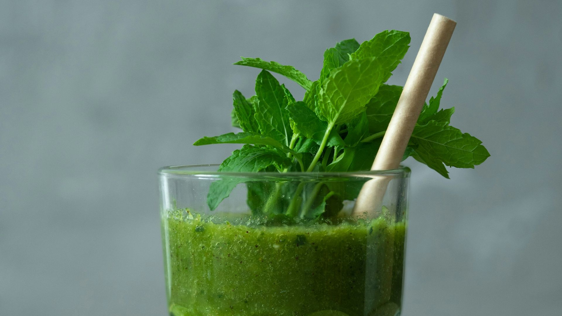 green liquid in clear drinking glass with straw