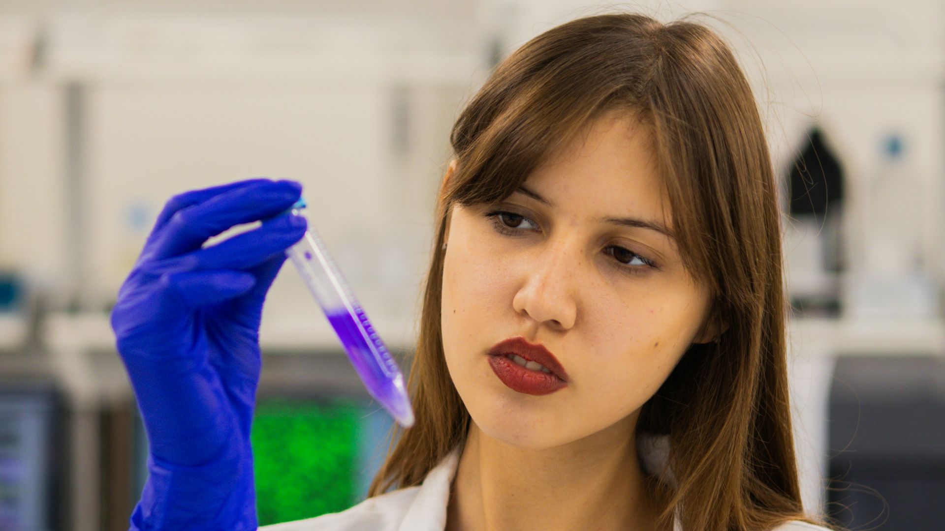 Scientist examines purple liquid in test tube