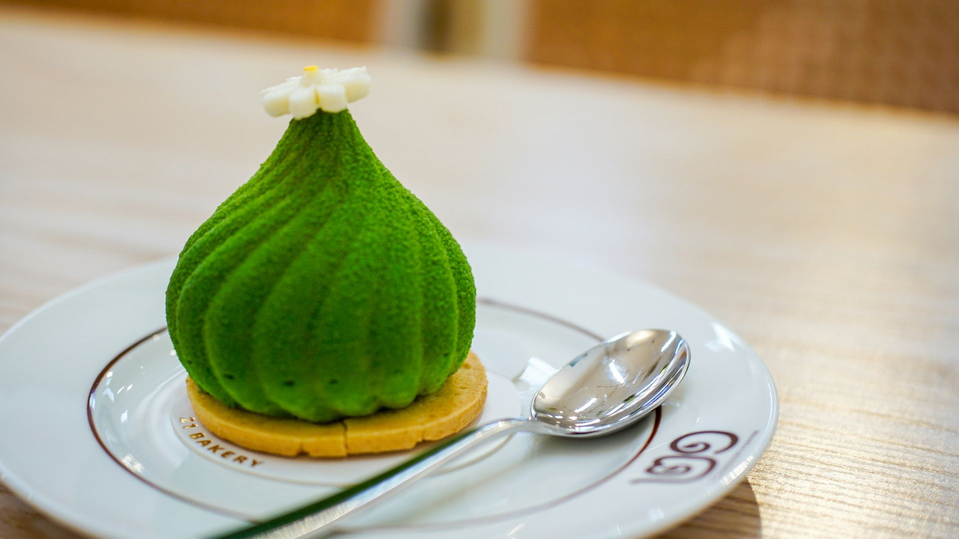 A green dessert with white flower topping on plate.