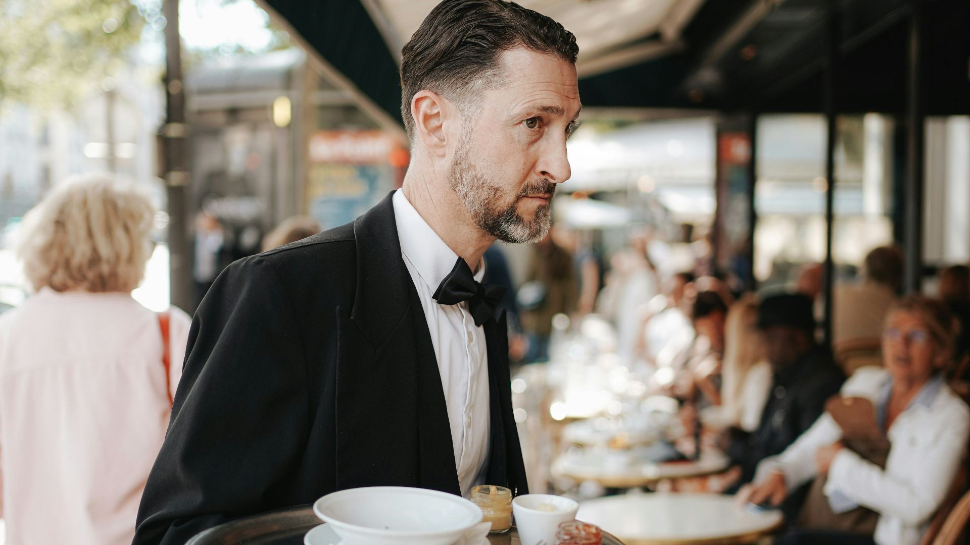 A man in a tuxedo carrying a tray of food