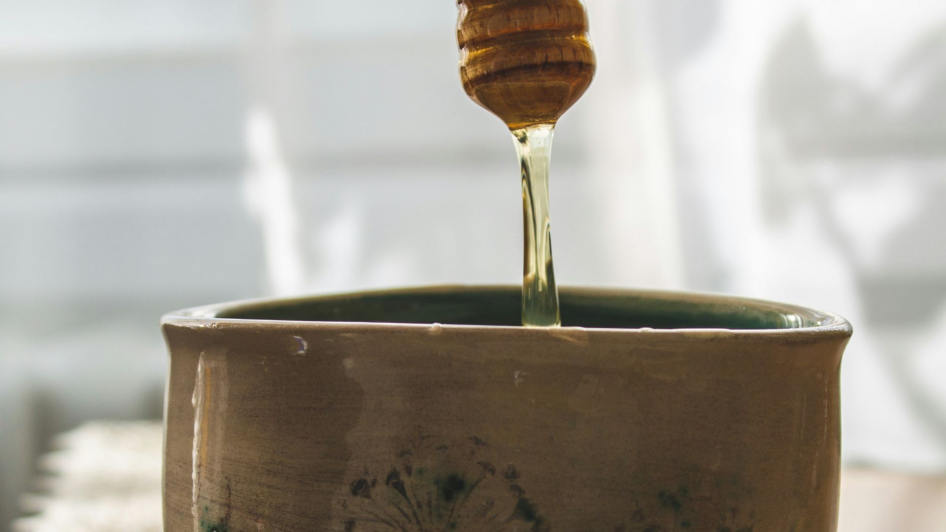 a spoon is pouring honey into a bowl