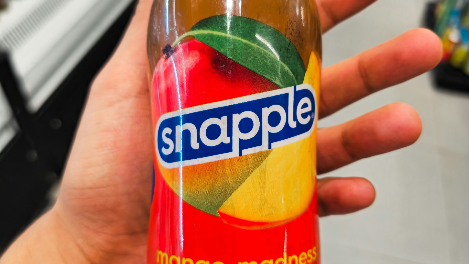 Hand holding a snapple mango madness drink bottle