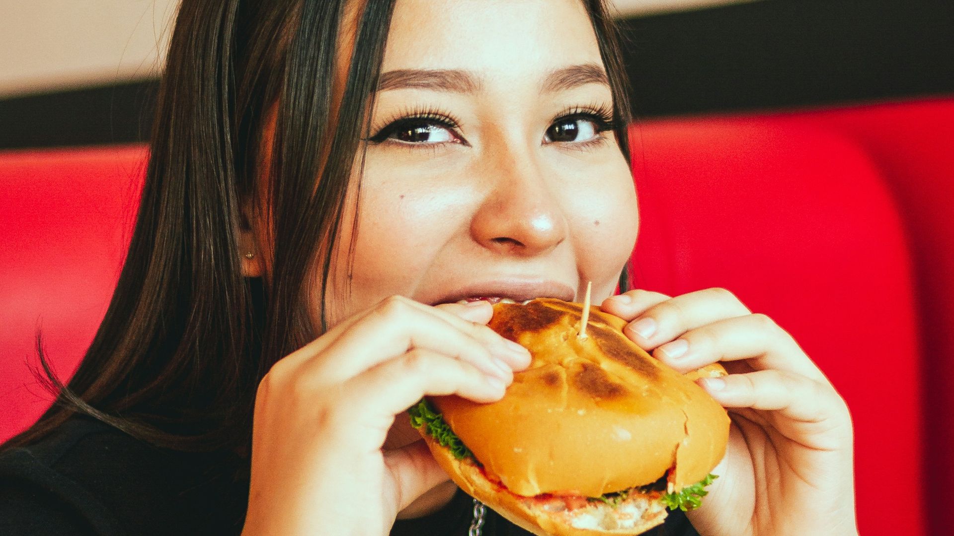 woman in black long sleeve shirt eating burger