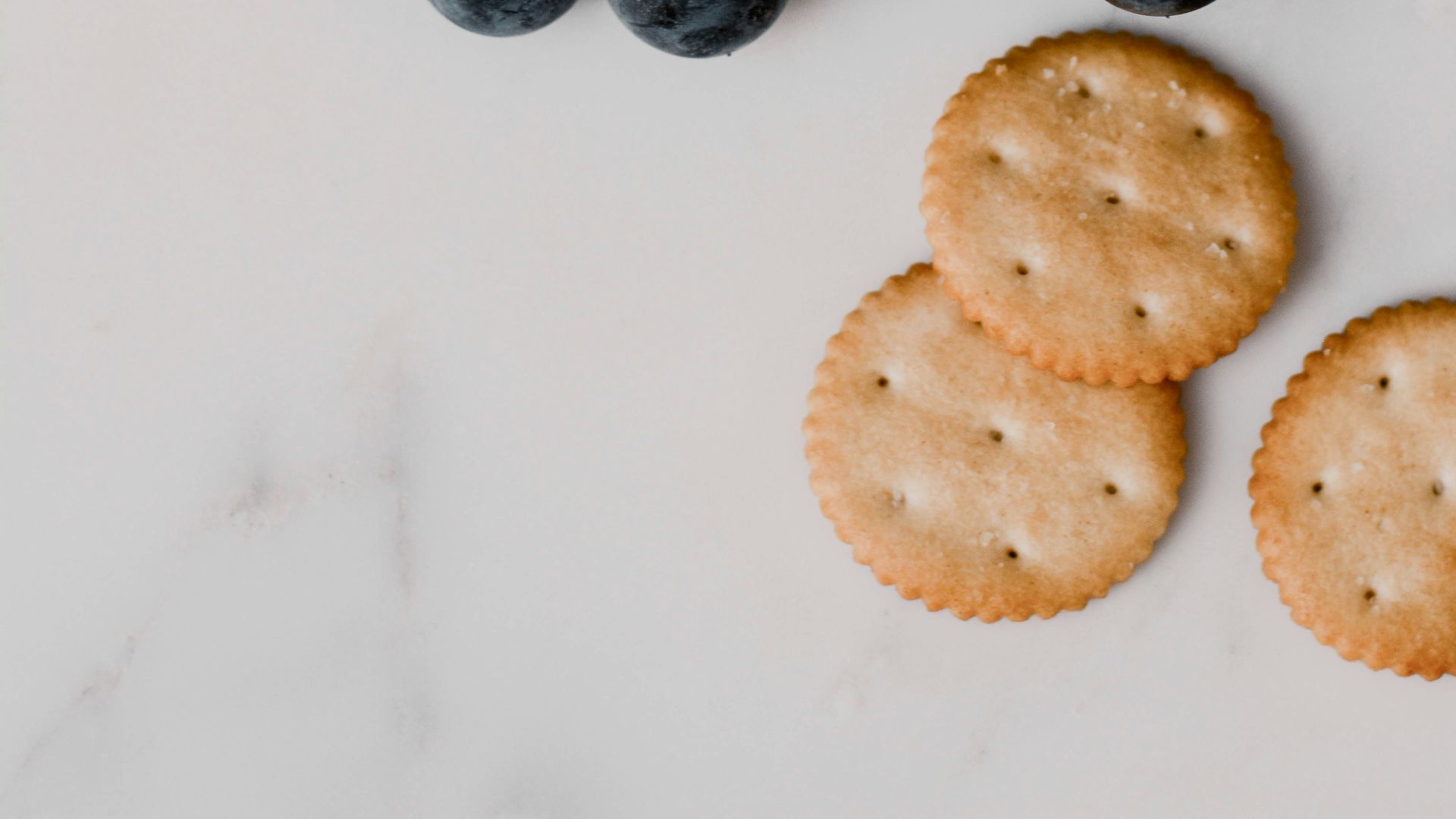 grapes, crackers and cheese on a marble surface