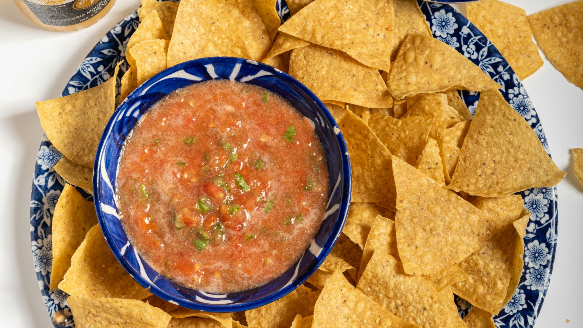 A plate of chips, salsa, and beer on a table