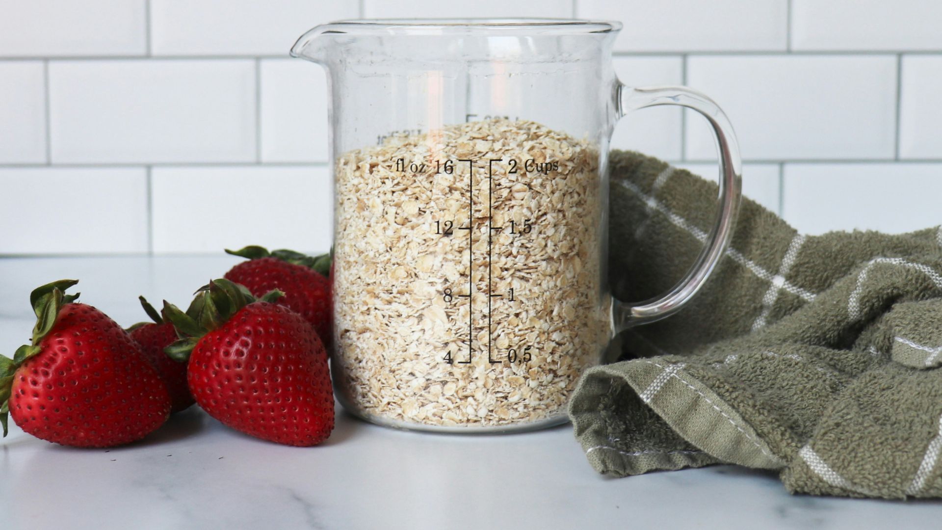 strawberries on white ceramic bowl beside clear glass pitcher