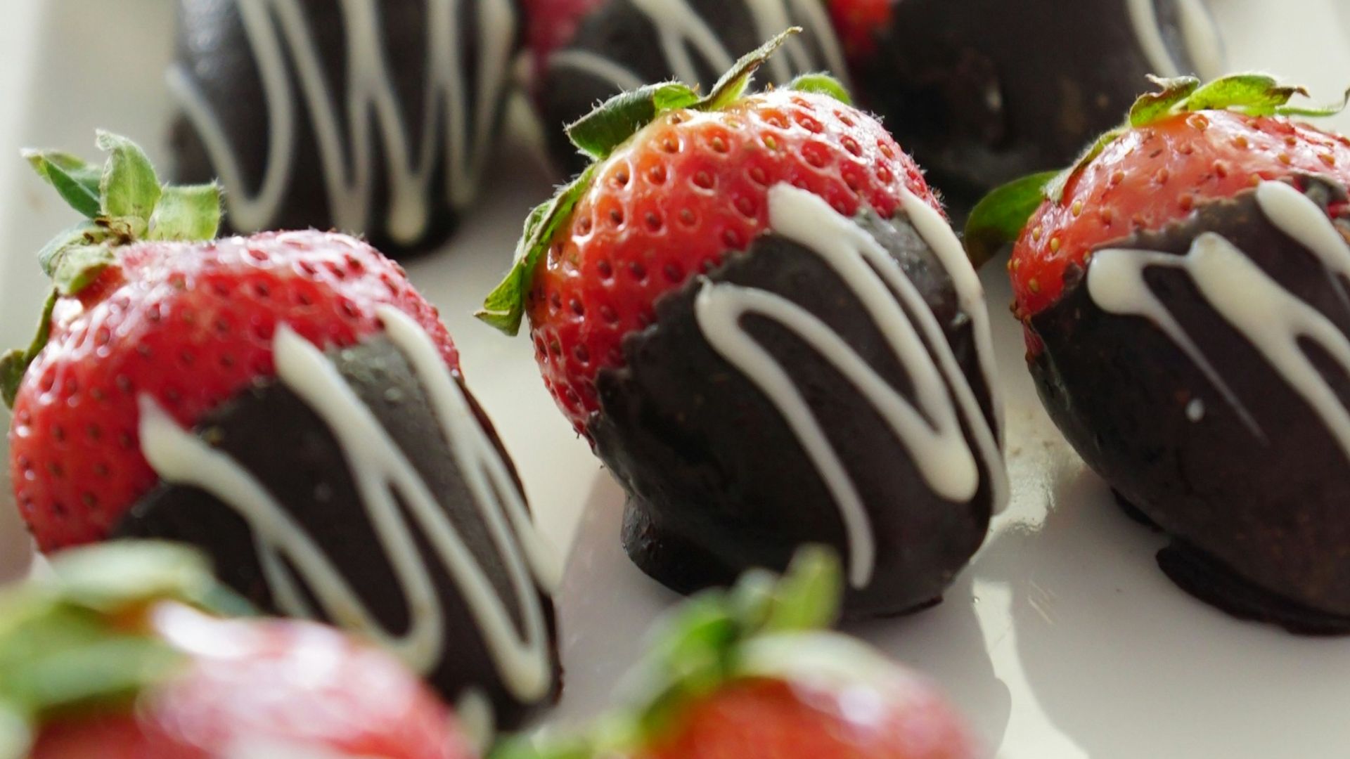 a plate of chocolate covered strawberries on a table