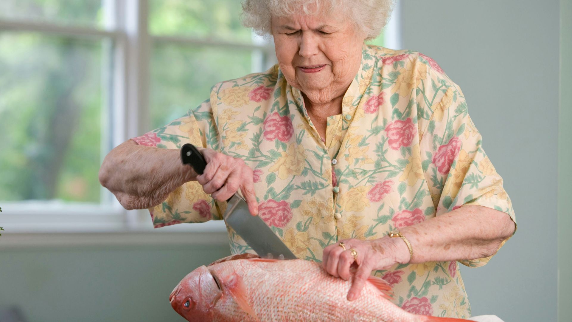 woman in yellow and pink floral shit holding a fresh fish