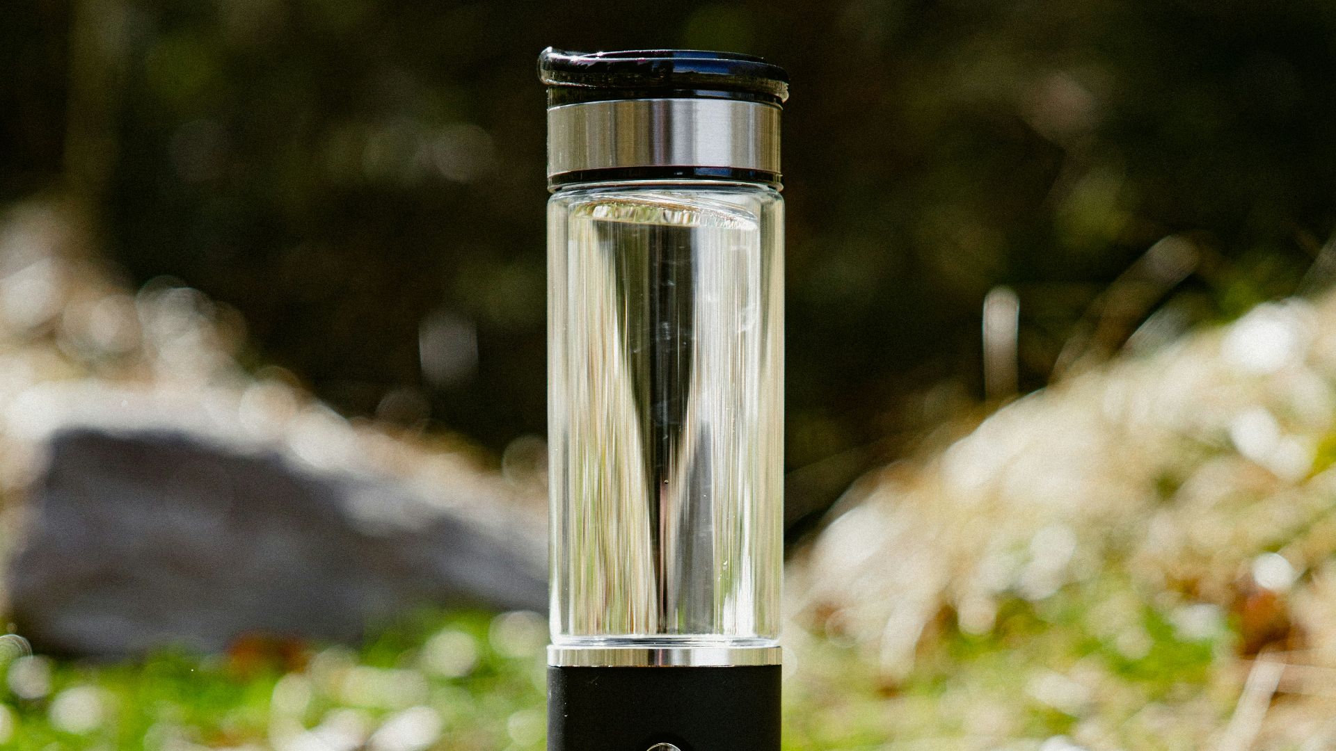 a glass water bottle sitting on top of a rock