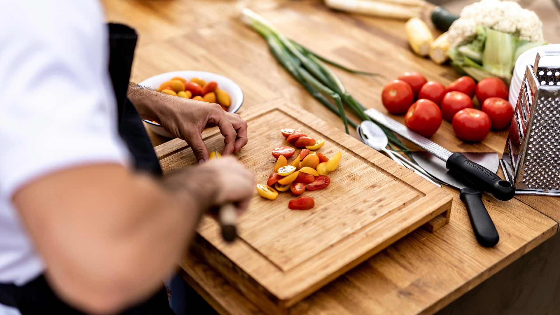 a person cutting up vegetables on a cutting board